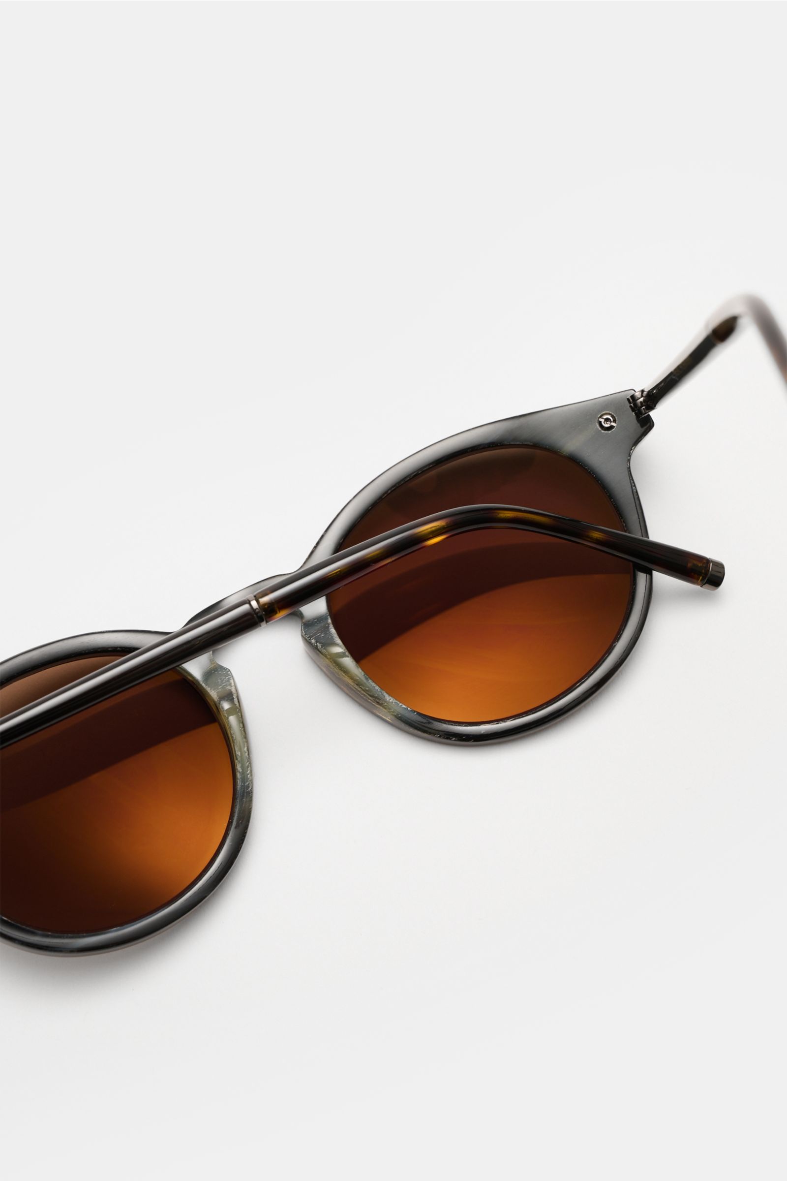 Nahaufnahme der Tom Ford Sonnenbrille 'Private Collection' schwarz/grau gemustert mit leicht gerundeter Silhouette und braunen Kunststoffgläsern, Acetat-Rahmen, 100% UV-Schutz, Filterkategorie 3, seitliche Perspektive.