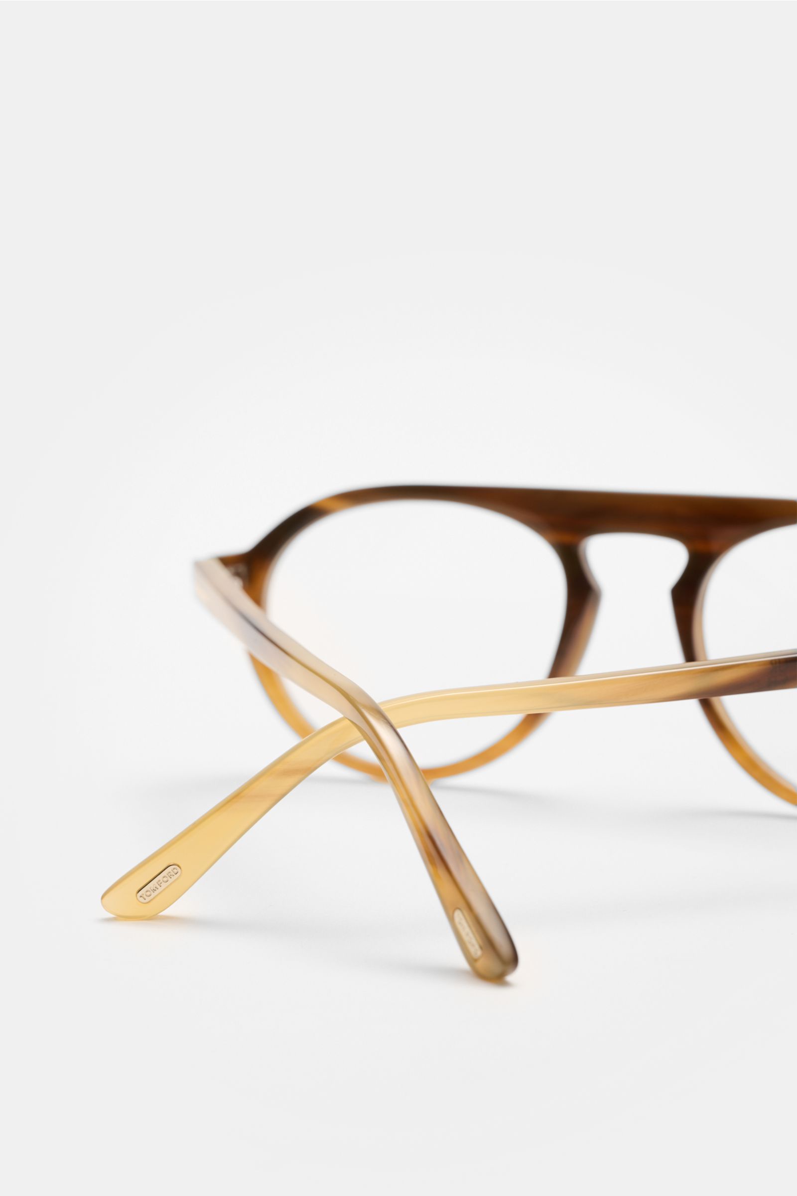 Close-up rear perspective of Tom Ford Horn Brille 'Private Collection' graubraun/sand gemustert with round shape, genuine buffalo horn frame, blue light filter lenses, T-shaped details, including leather hard case, horn polish set, and cleaning cloth; a s