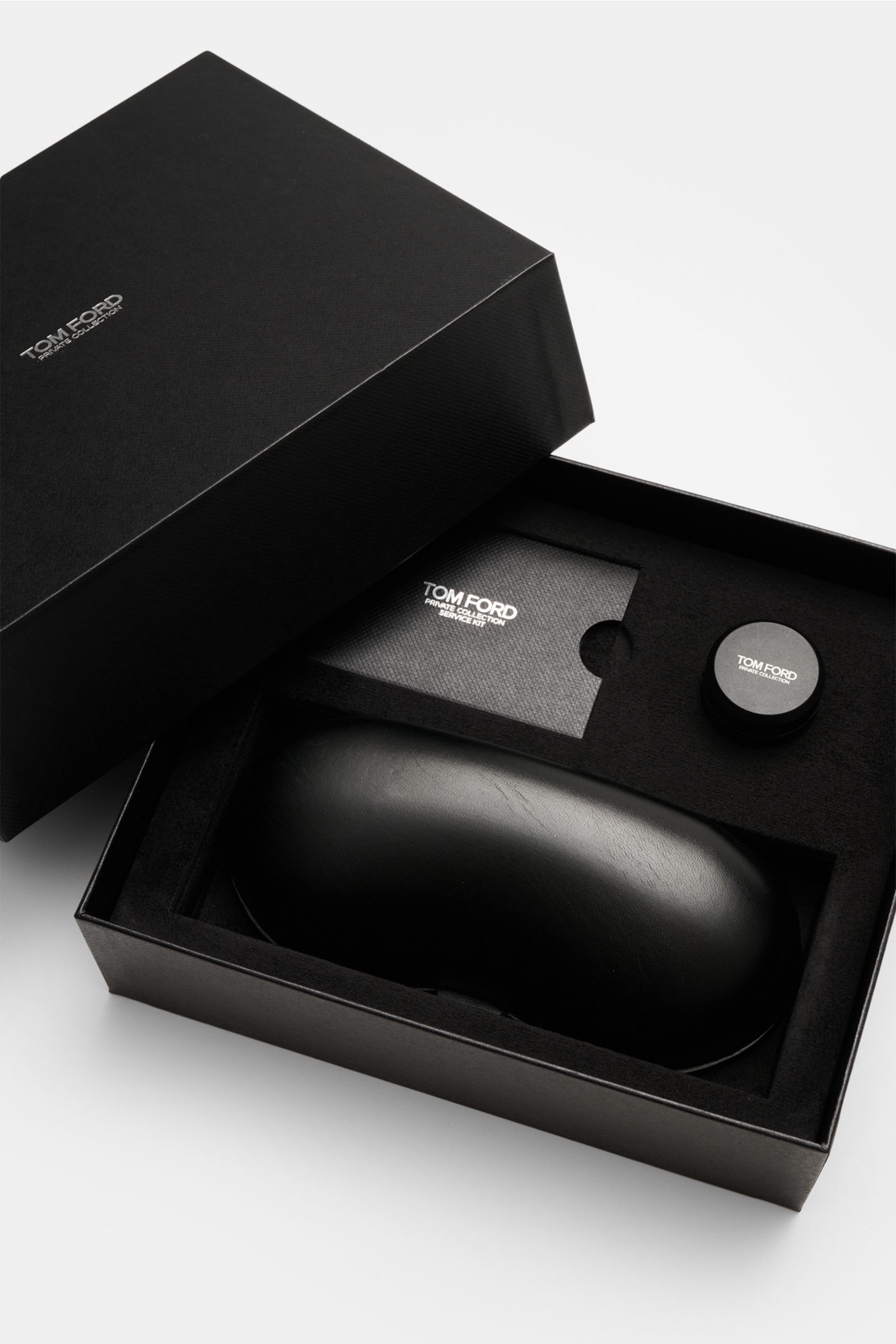 Black Tom Ford Horn Brille 'Private Collection' graubraun/sand gemustert case and accessories displayed from above, including leather hard case, polishing set, and cleaning cloth.

Description incorporated: Stylish eye-catcher: The exclusive horn glasses 