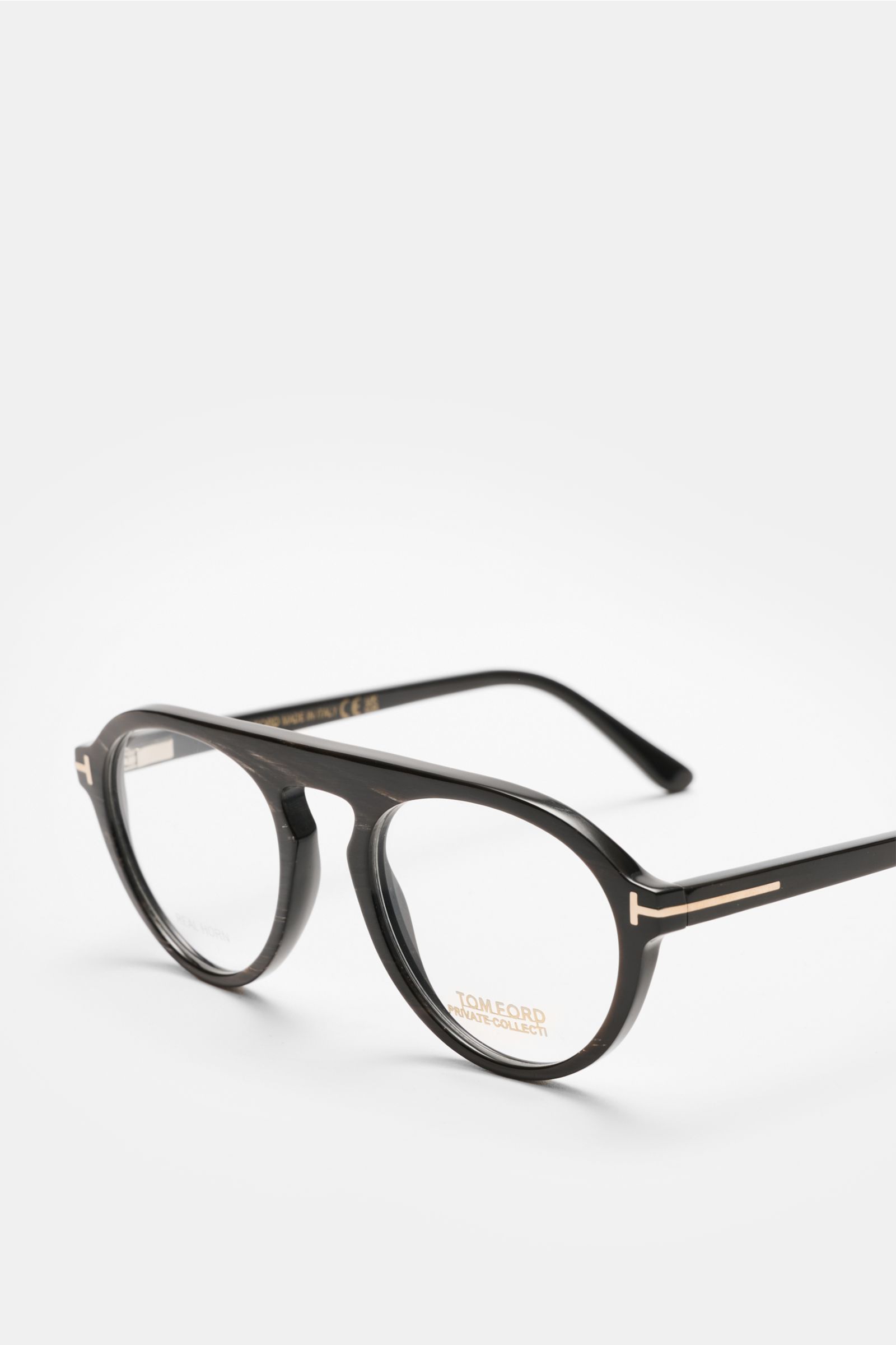 Tom Ford Horn Brille 'Private Collection' schwarz/grau/weiß gemustert shown from a front-side angle, round horn frame with blue light filter lenses, T-shaped details, includes leather hard case, horn polish set, and cleaning cloth. Stilvoller Eyecatcher: 
