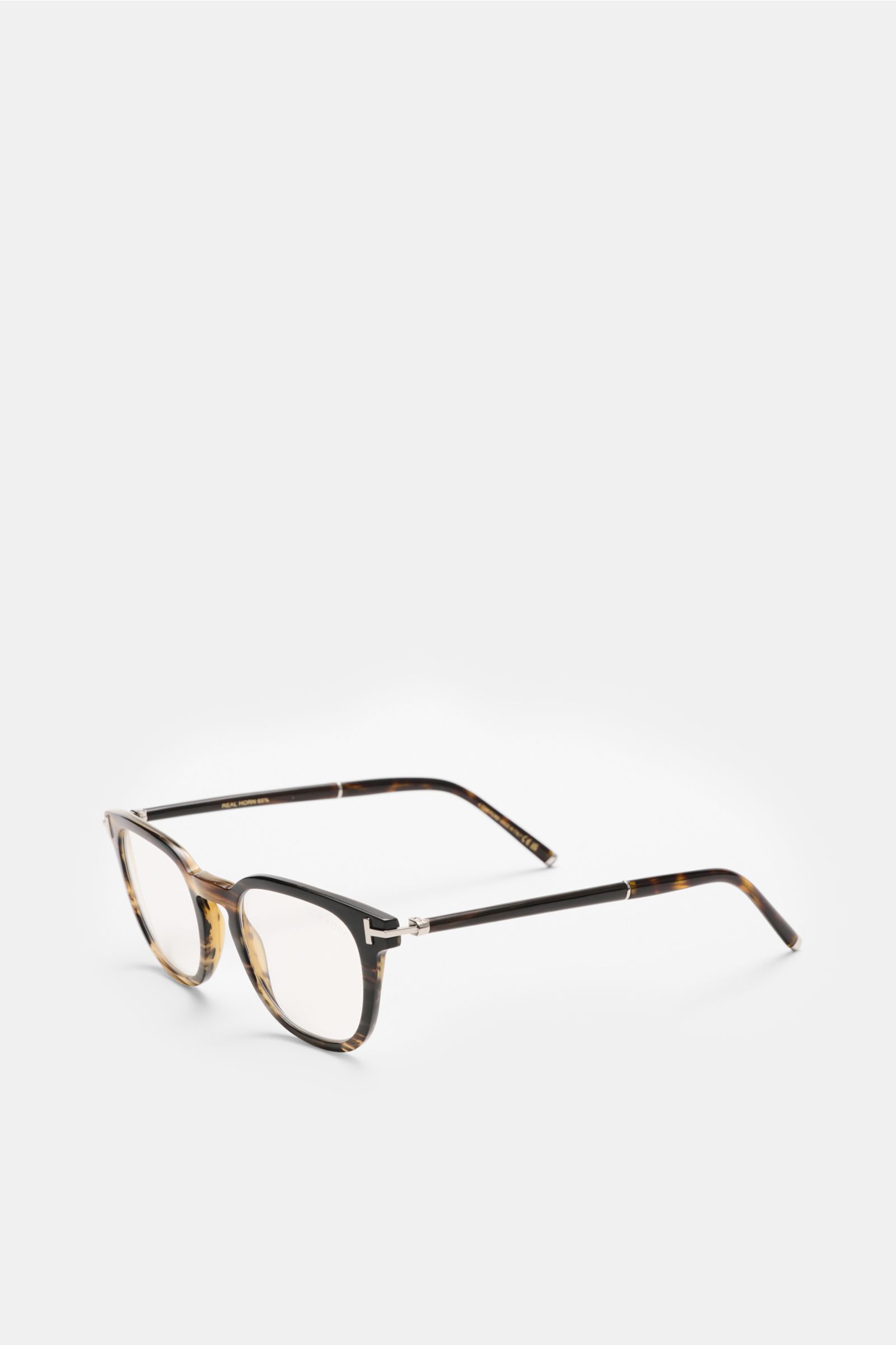 Tom Ford Horn Brille 'Private Collection' schwarz/braun/sand gemustert shown from a front-side angle, featuring a slightly rounded silhouette, real buffalo horn frame, blue light filter lenses, T-shaped details, and includes a leather hard case, horn poli