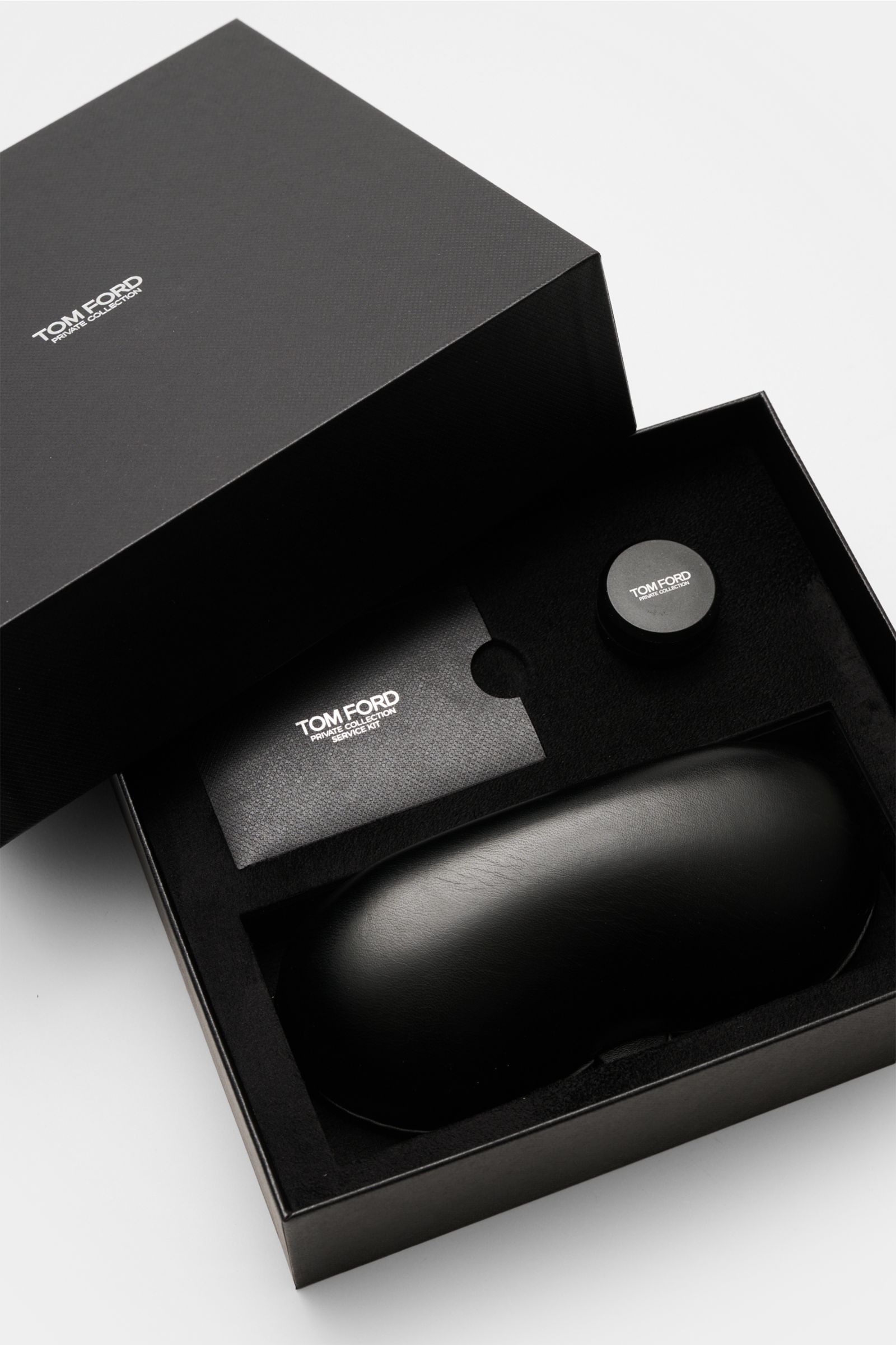 Top-down view of the Tom Ford Horn Brille 'Private Collection' schwarz packaging including leather hard case, horn polish set, and cleaning cloth.

Description: Stilvoller Eyecatcher: Die exklusive Horn Brille aus der 'Private Collection' von TOM FORD 
