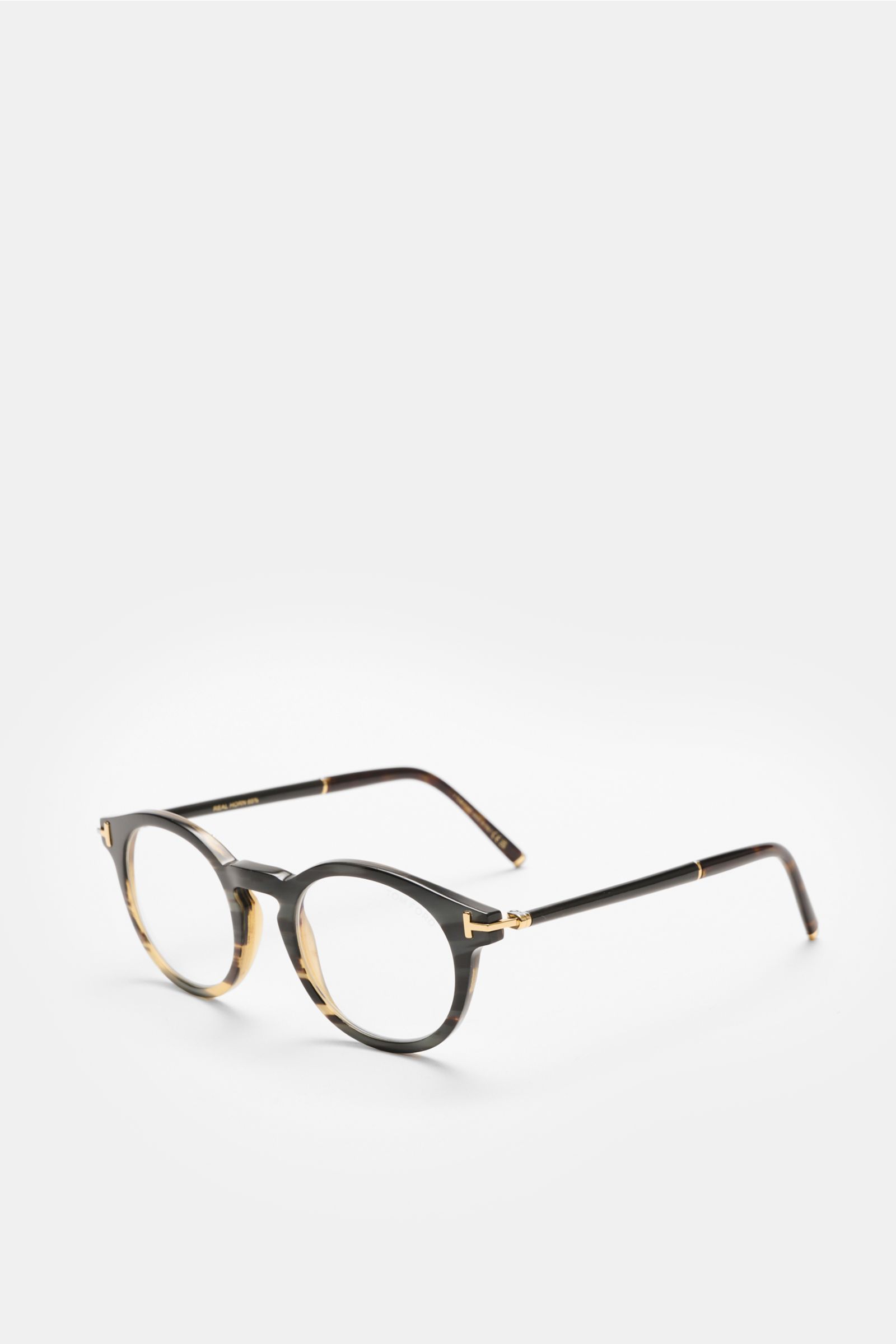 Front angled view of Tom Ford Horn Brille 'Private Collection' schwarz/grau gemustert, a stylish round horn frame with blue light filter lenses, T-shaped details, including leather case, horn polish set, and cleaning cloth.