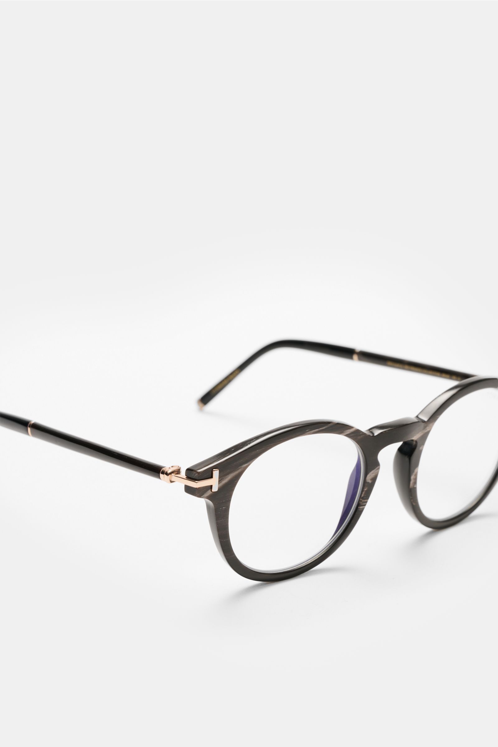 Tom Ford Horn Brille 'Private Collection' schwarz/graubraun/weiß gemustert shown from a close-up side angle, featuring a round design with genuine buffalo horn frame, blue light filter lenses, T-shaped details, and described as stylish and practical workp