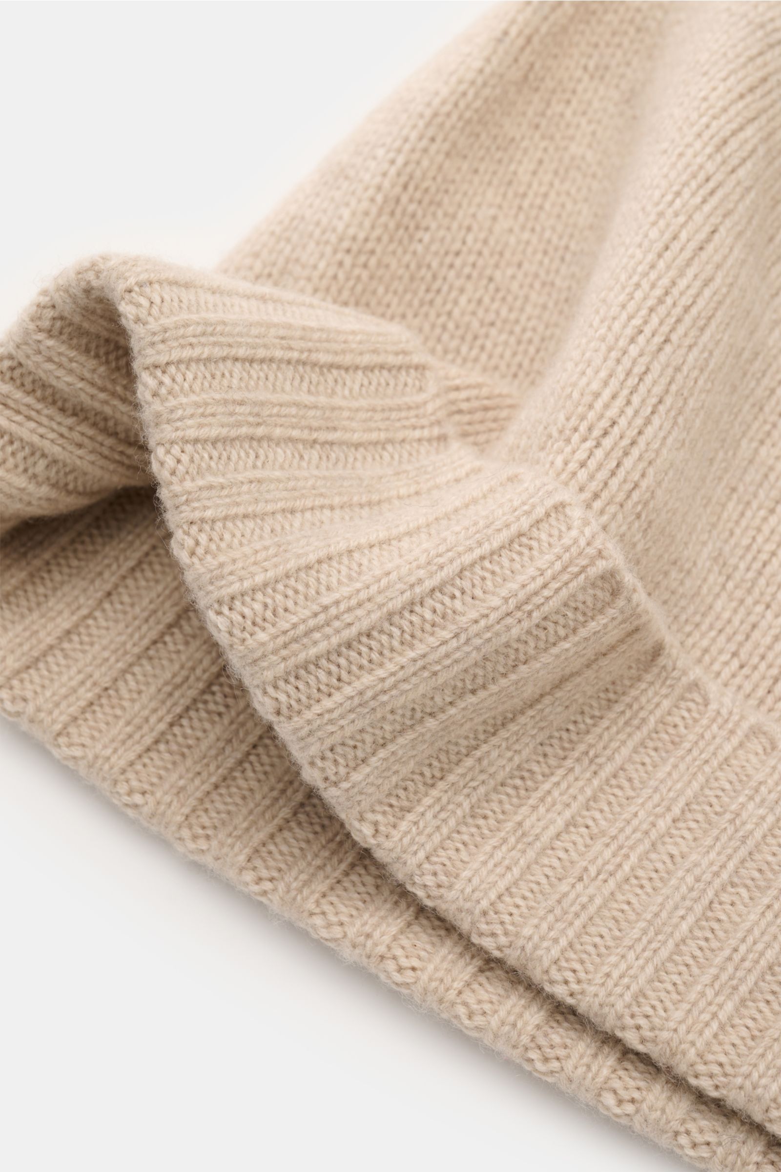 Nahaufnahme der von Braun Cashmere Mütze sand mit feinem Strickbild und schmalem Umschlag, reiner Cashmere, sehr weicher Griff, von schräg oben fotografiert.