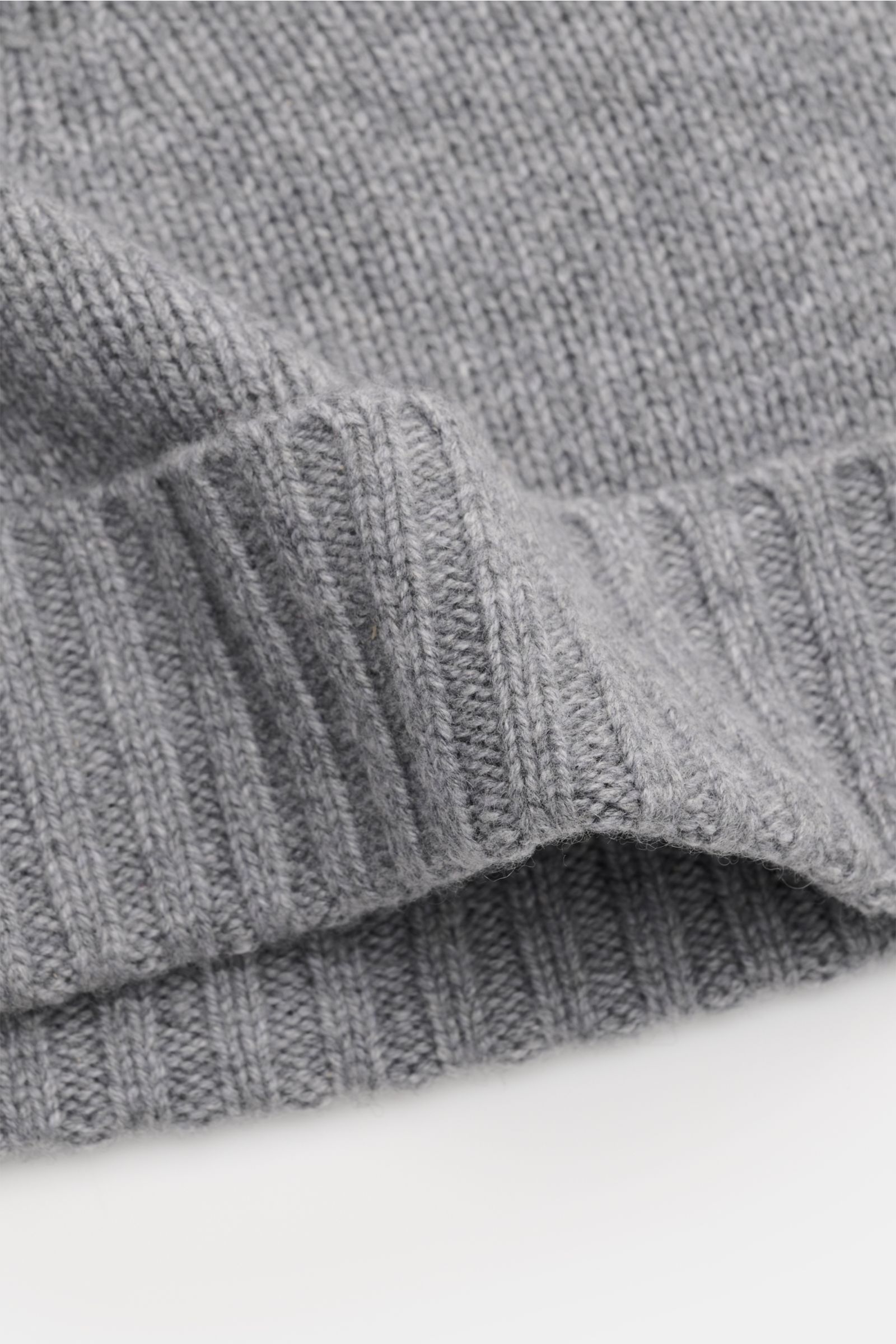 Close-up of the ribbed edge and fine knit texture of the von Braun Cashmere Mütze hellgrau meliert, shown from a side angle. Egal, ob zum klassischen Wintermantel oder zur hochfunktionalen Daunenjacke: diese softe VON BRAUN Strickmütze aus reinem Cashmere