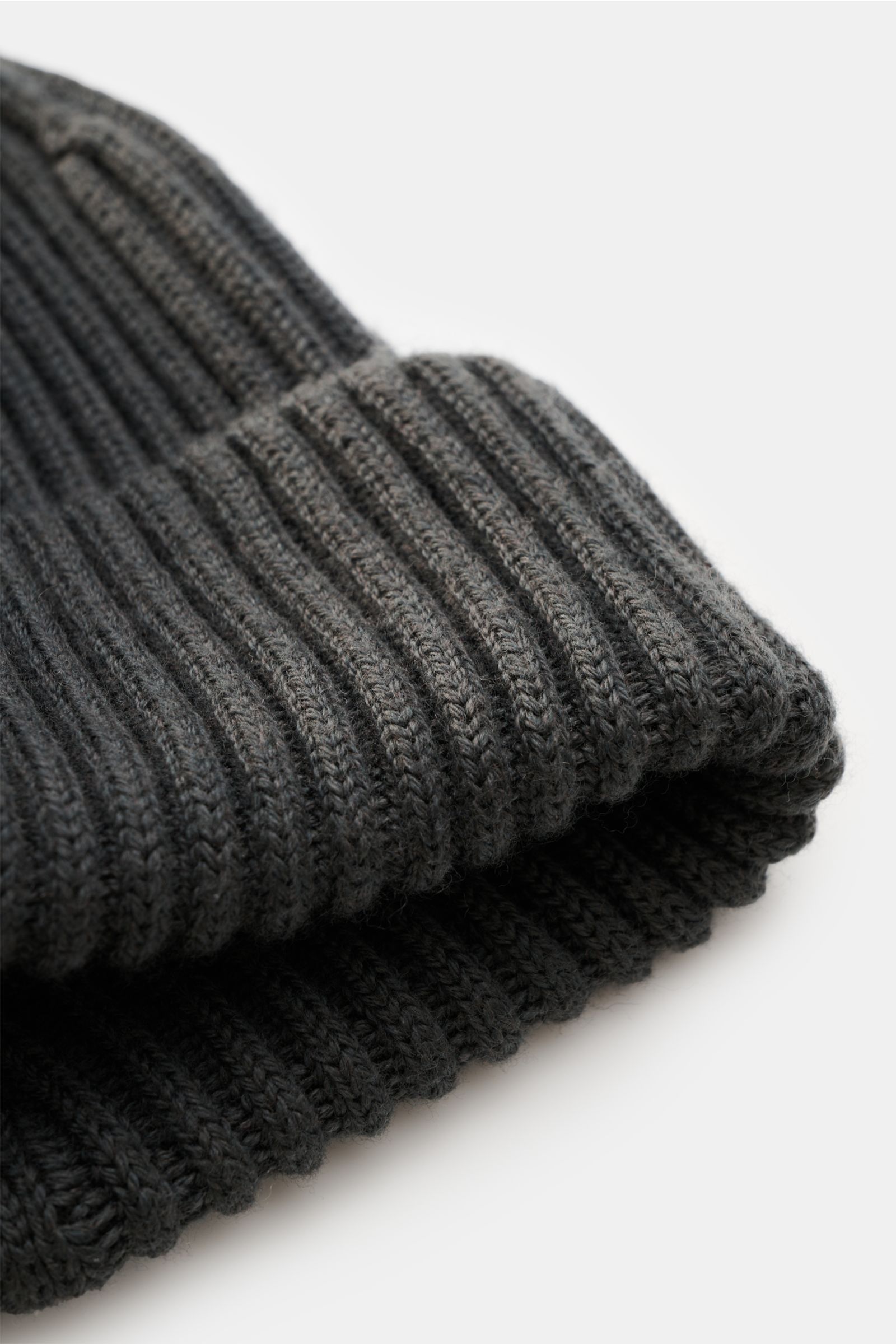 Stone Island Wollmütze dunkelgrau, Nahaufnahme von schräg oben, reine Wolle, weicher Griff, moderne Rippstrick-Optik, breiter Umschlag, Front mit STONE ISLAND-Weblabel.