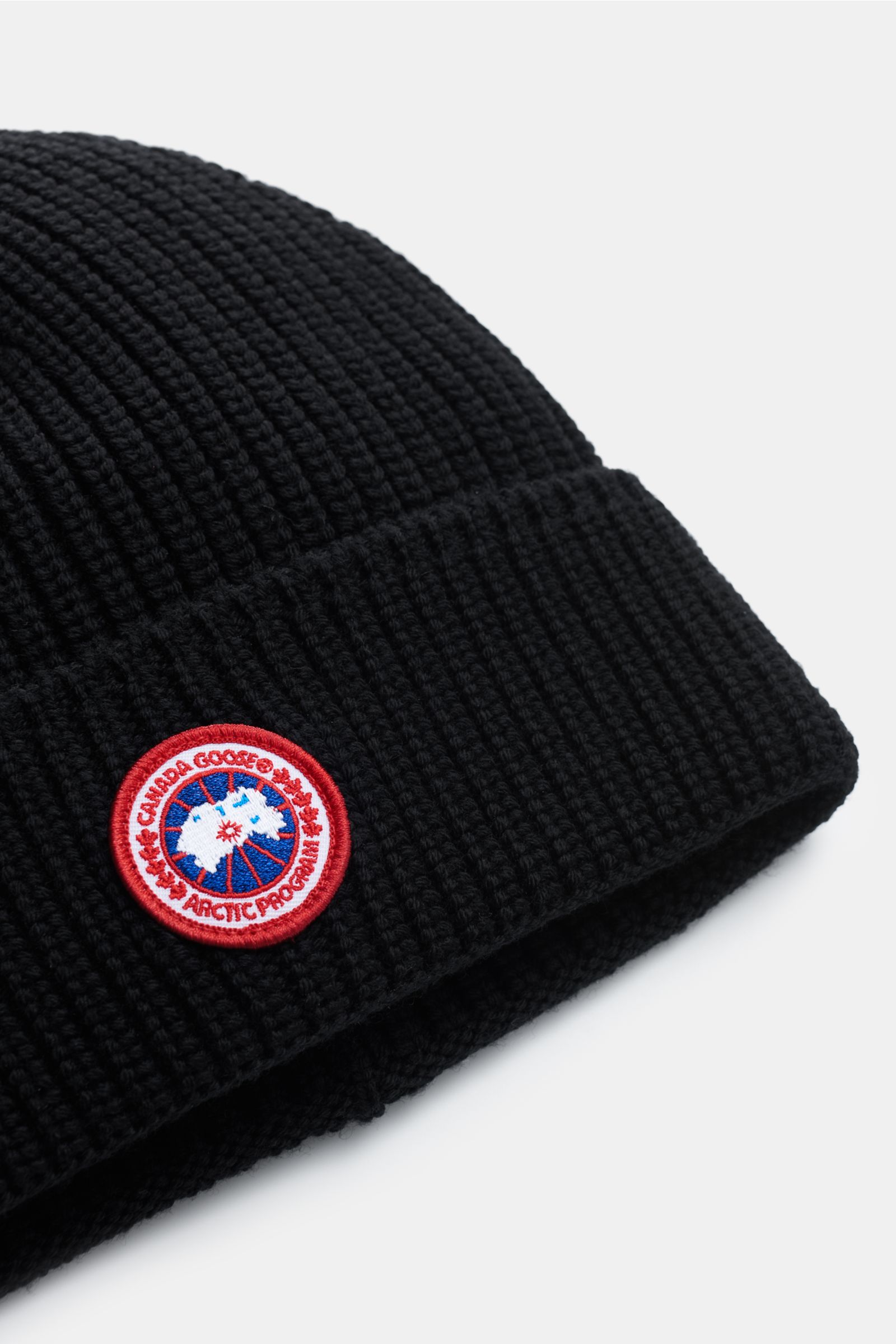 Canada Goose Wollmütze schwarz aus grobem Rippstrick, reine Wolle, griffige Qualität, mit Umschlag und Weblabel, seitliche Nahaufnahme.