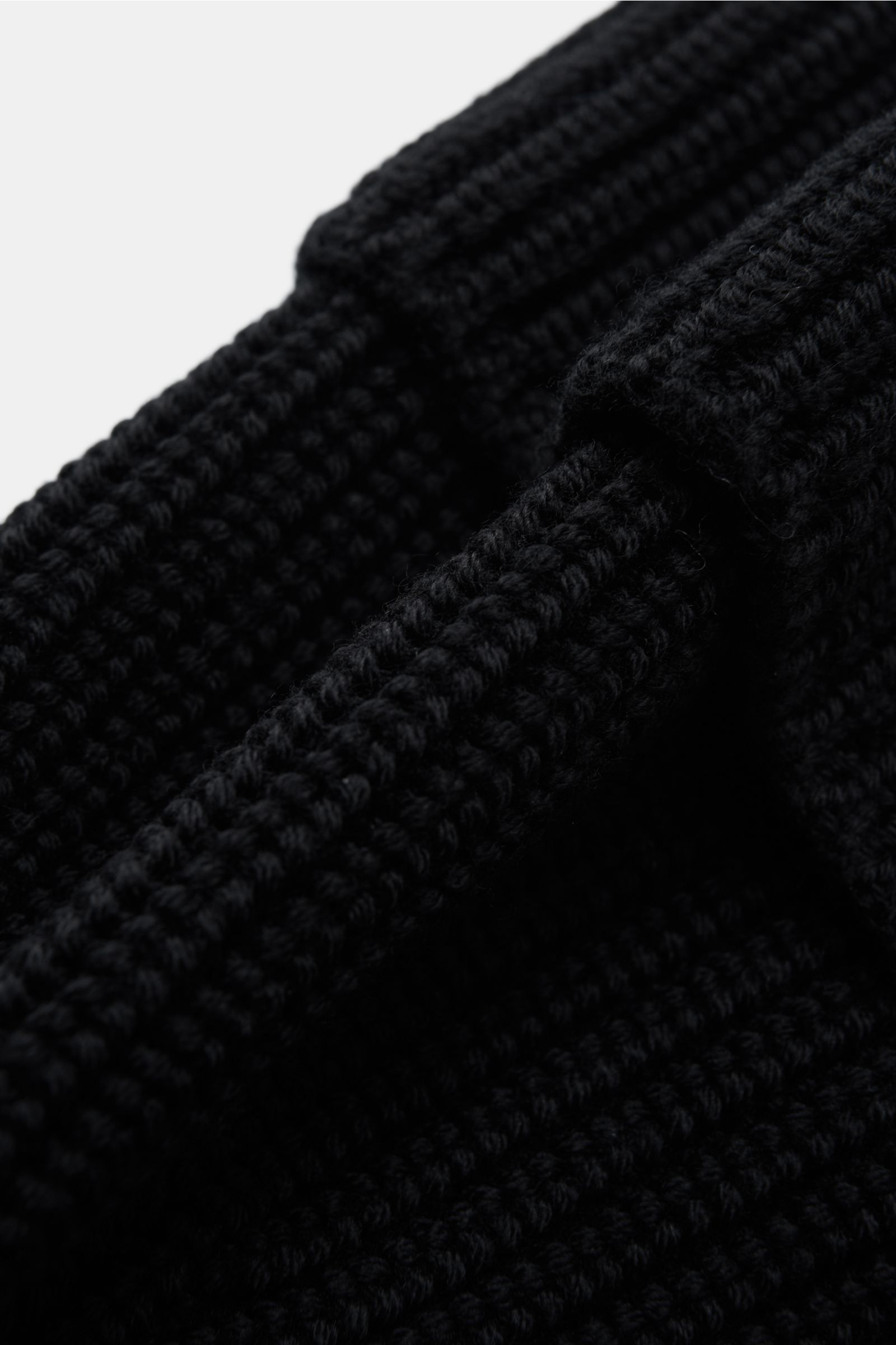 Canada Goose Wollmütze schwarz aus grobem Rippstrick, reine Wolle, griffige Qualität, Umschlag mit Weblabel, Detailaufnahme von schräg oben.