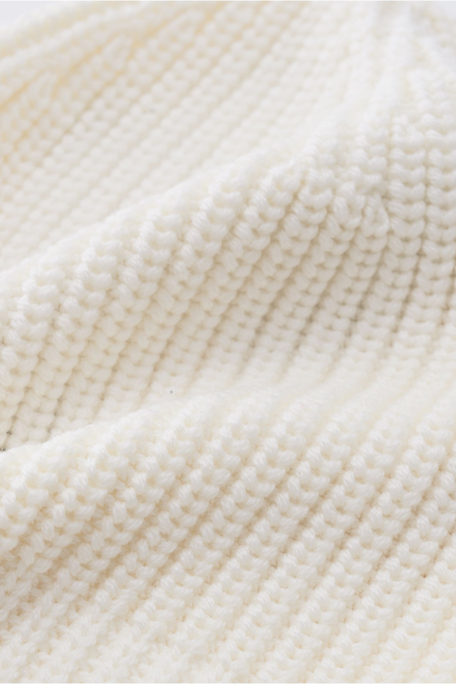 Nahaufnahme der Canada Goose Wollmütze creme aus grobem Rippstrick, reiner Wolle mit Umschlag und Weblabel, griffige Qualität.