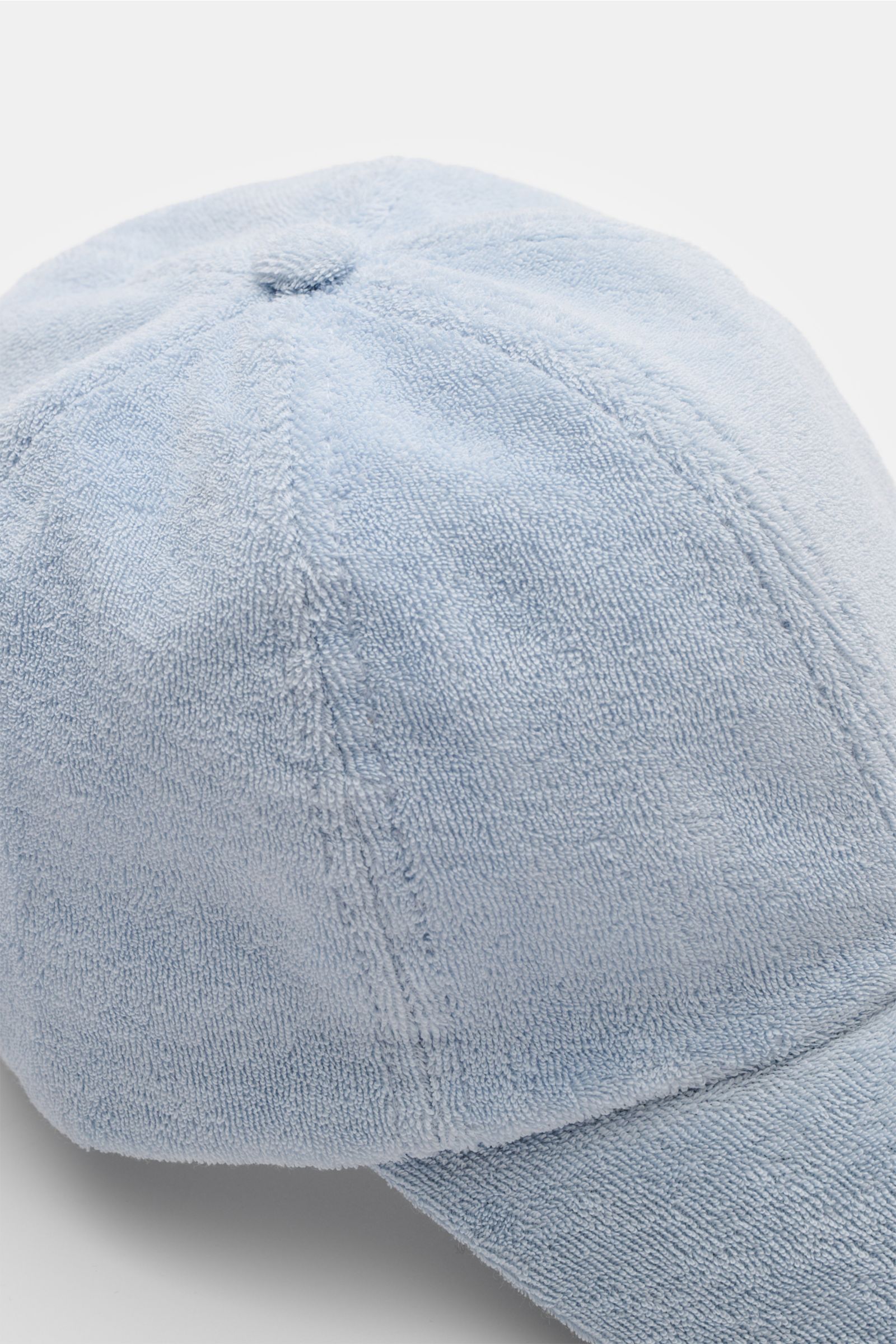 Close-up top-front view of the 04651/ A trip in a bag Frottee-Cap 'Oyster' hellblau, a light blue terry cotton baseball cap with soft texture, subtle back label, and adjustable strap, perfect for beach days or promenade strolls. Das sportlich-stylishe 