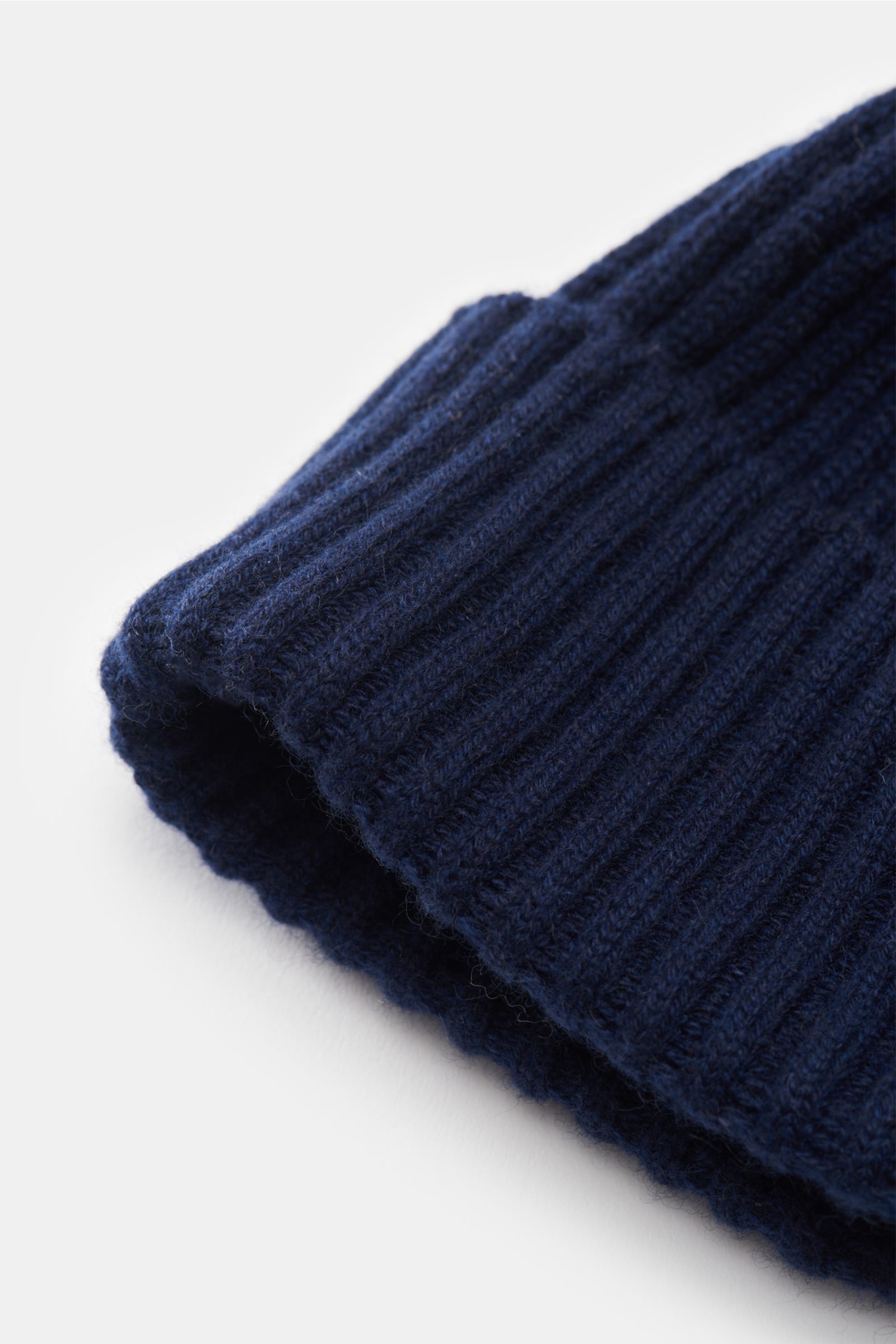 Close-up front-side view of a navy ribbed knit Brunello Cucinelli Cashmere Mütze navy with wide cuff, showing soft pure cashmere texture. Diese Mütze aus edlem Cashmere im zeitlosen Rippstrick-Design von BRUNELLO CUCINELLI bringt behagliche Wärme und l