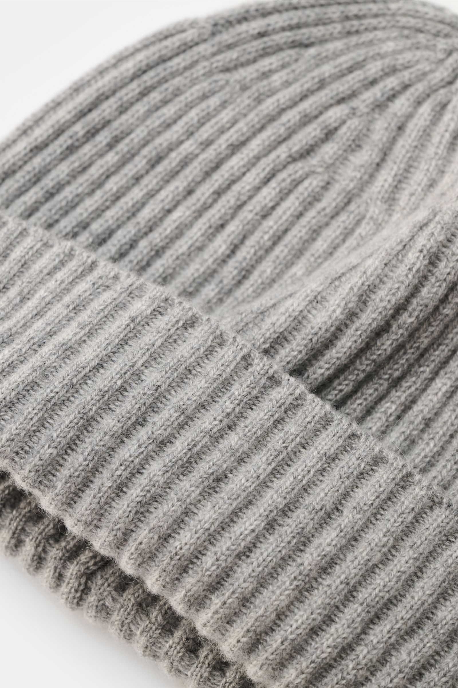 Brunello Cucinelli Cashmere beanie light grey mottled shown from a close-up top angle, highlighting the ribbed knit and wide turn-up. This beanie in fine cashmere and a timeless ribbed knit by BRUNELLO CUCINELLI brings cosy warmth and luxurious comfort