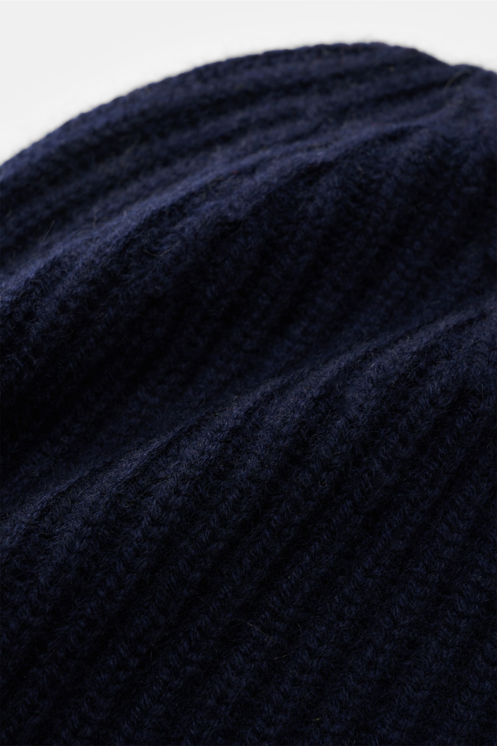 Close-up view of the Lisa Yang Cashmere Mütze 'Menton' navy showing its soft, pure cashmere fabric with a medium-gauge patent knit pattern and classic cuff. Luxus für kalte Tage – die Mütze 'Menton' von LISA YANG bringt Wärme und Stil in Ihr Winter-Outfit