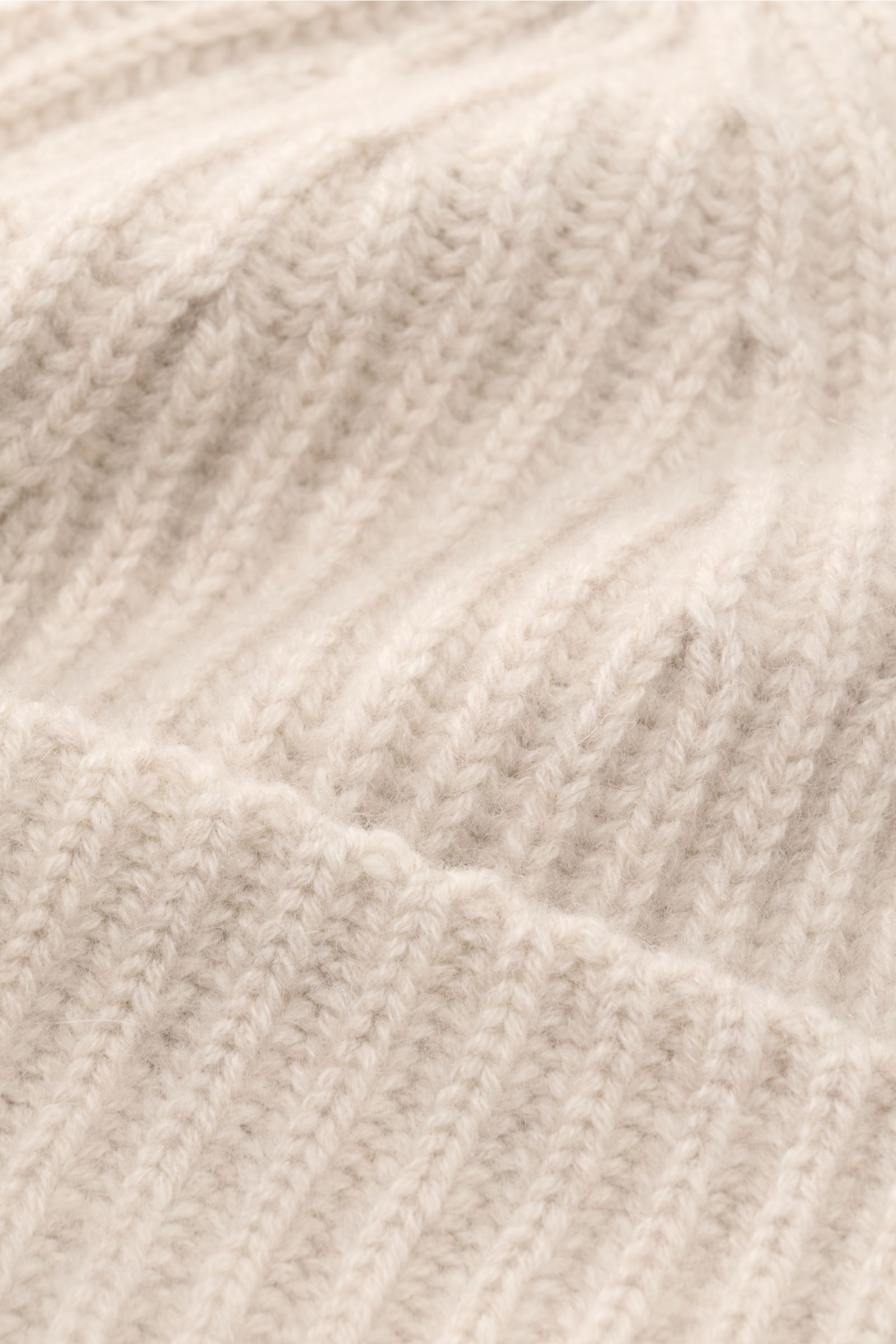 Close-up top-down view of the Lisa Yang Cashmere Mütze 'Menton' sand showcasing its soft pure cashmere fabric, medium knit texture, distinctive patent stitch pattern, and classic cuff. Luxus für kalte Tage – die Mütze 'Menton' von LISA YANG bringt Wärme u