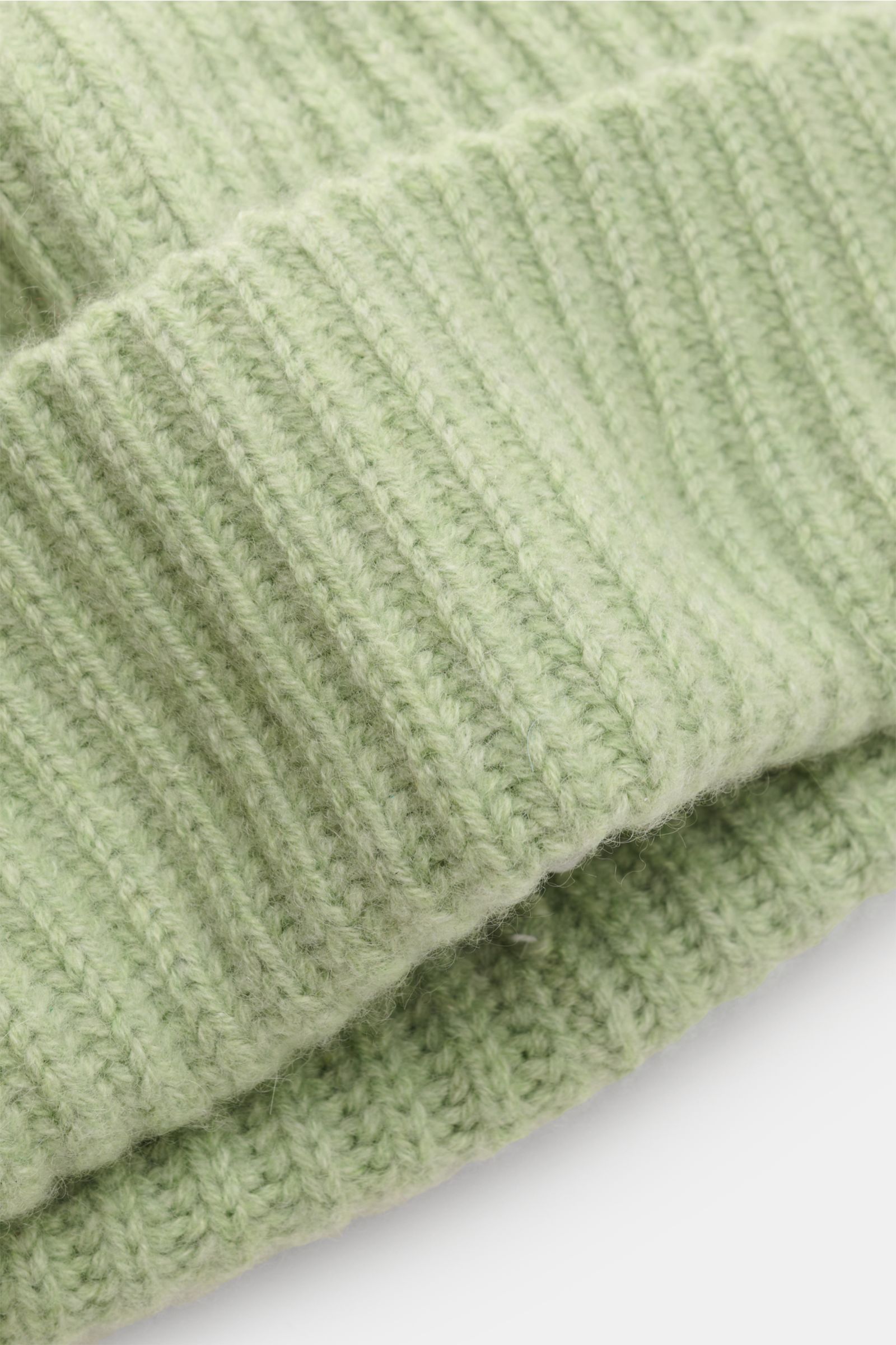 Close-up side view of the Lisa Yang Cashmere Mütze 'Menton' hellgrün, showcasing its pure cashmere, soft feel, patent knit pattern, medium knit texture, and classic cuff design. Luxus für kalte Tage – die Mütze 'Menton' von LISA YANG bringt Wärme und Stil
