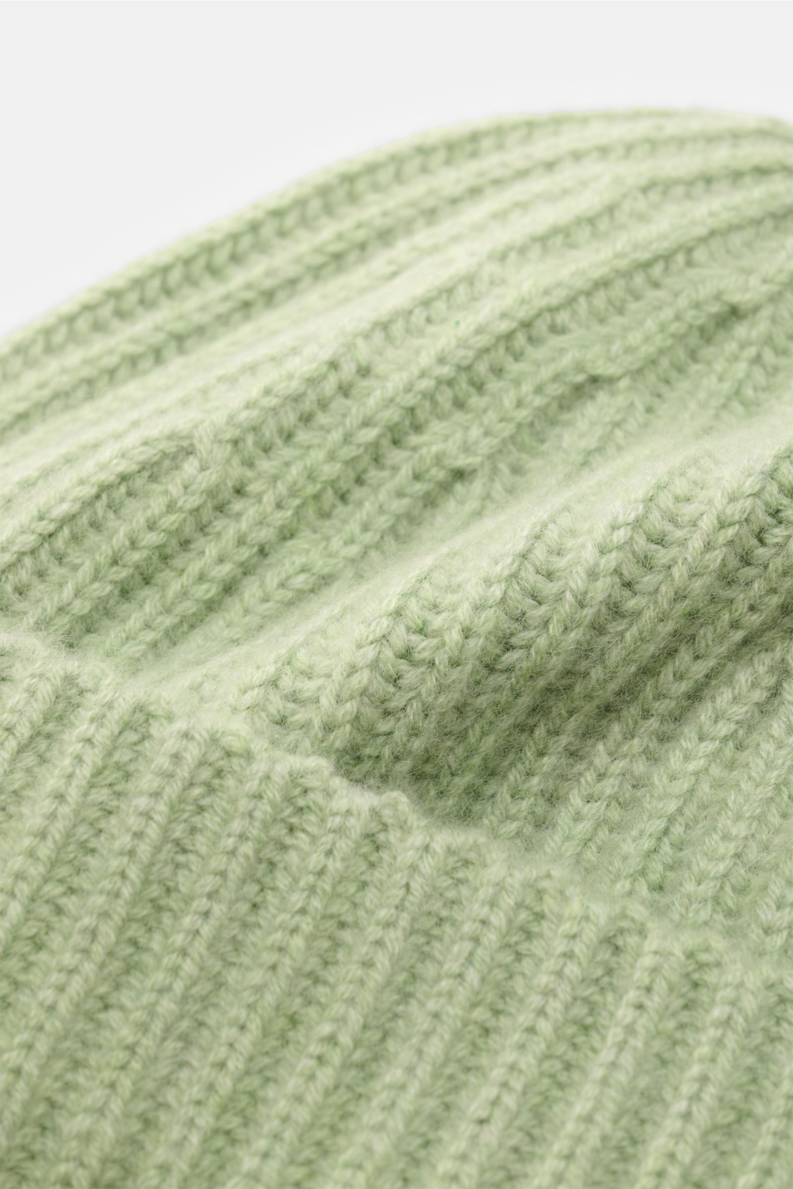 Close-up image of the Lisa Yang Cashmere Mütze 'Menton' hellgrün, showing the soft, ribbed patent-knit pattern and classic cuff from a top-side perspective. Luxus für kalte Tage – die Mütze 'Menton' von LISA YANG bringt Wärme und Stil in Ihr Winter-Outfit