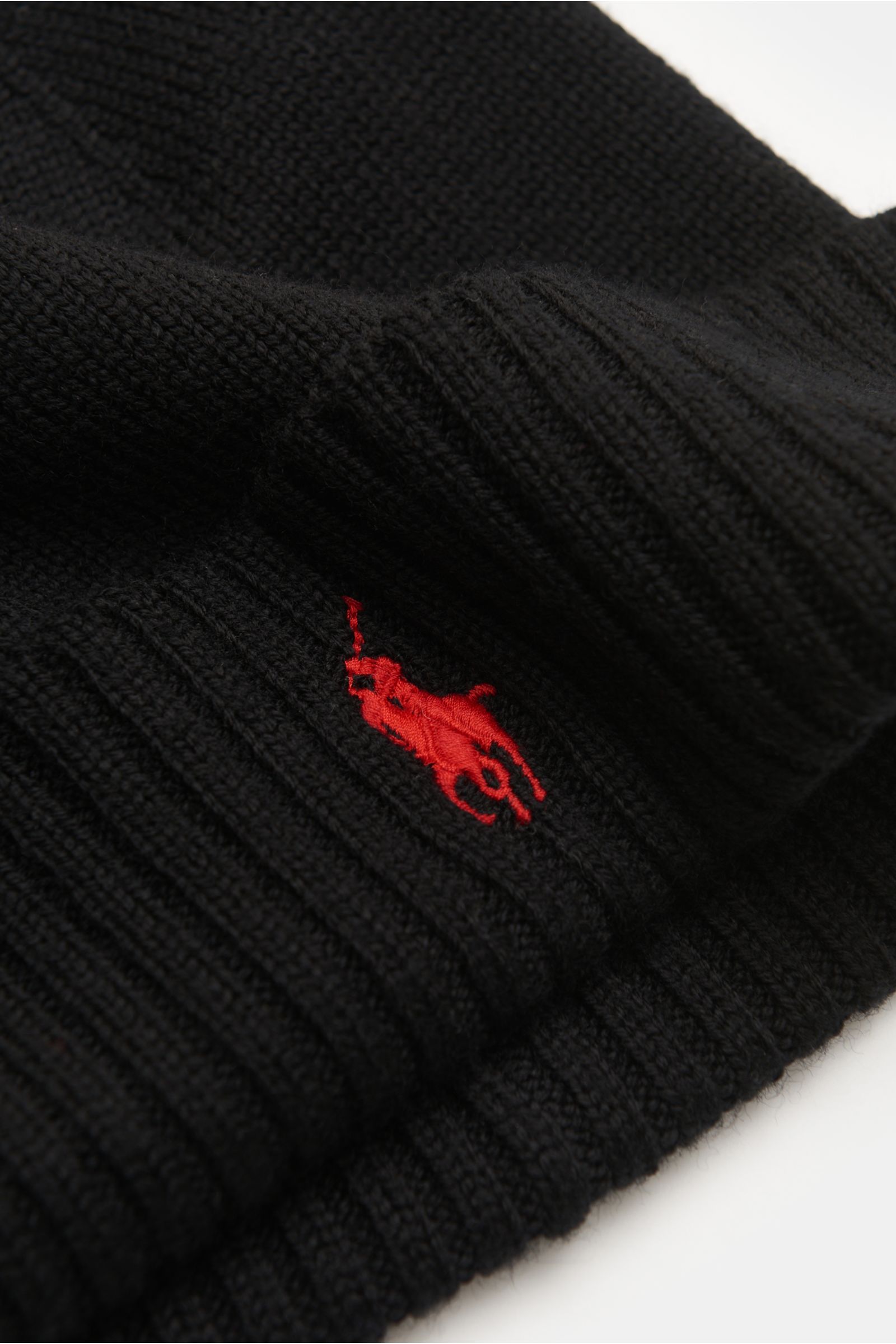 Close-up angled view of Polo Ralph Lauren Wollmütze schwarz, a finely knitted black wool hat with soft texture, ribbed cuff, and red polo player stitching.

Description: Sportives Essential von POLO RALPH LAUREN: Mit dieser fein gestrickten Mütze aus r