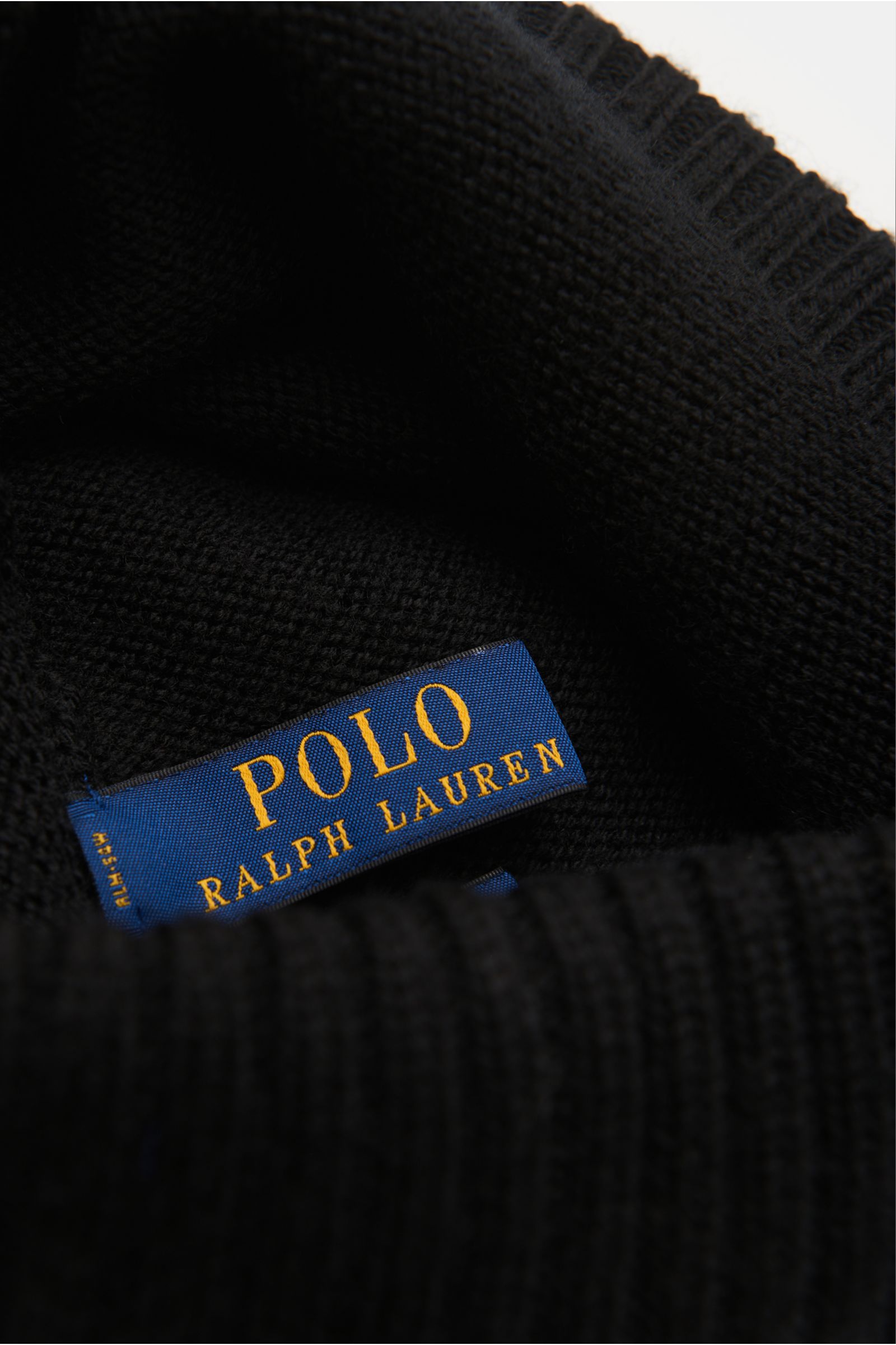 Close-up inside view of Polo Ralph Lauren Wollmütze schwarz showing the blue label, fine smooth knit, and wide ribbed cuff.

Description:  
Sportives Essential von POLO RALPH LAUREN: Mit dieser fein gestrickten Mütze aus reiner Wolle sind Sie garantier