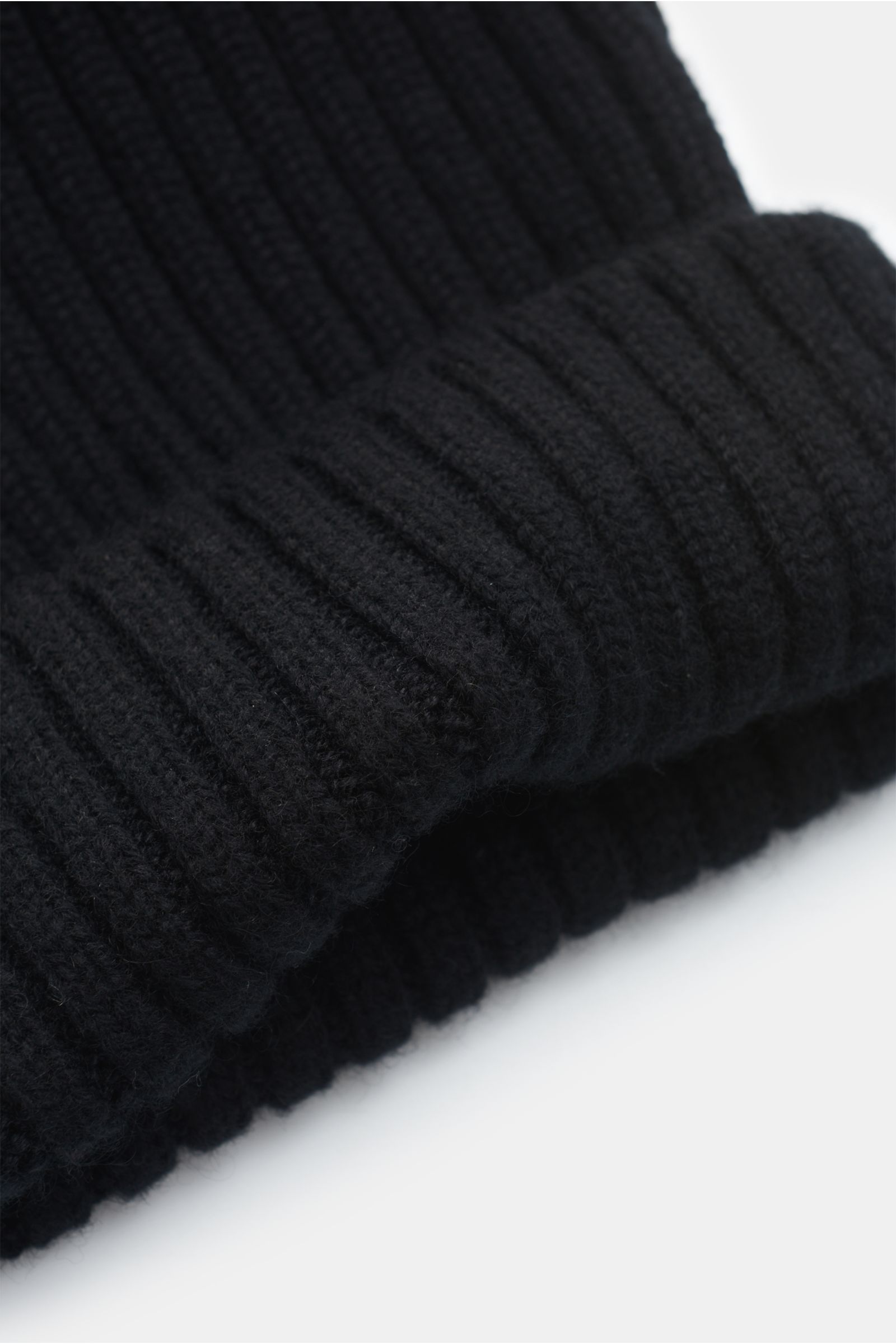 Fedeli Cashmere Mütze schwarz, Nahaufnahme seitlich unten, breiter Rippstrick, mittelfeines Strickbild, reiner Cashmere mit weichem Griff, variabler Umschlag.