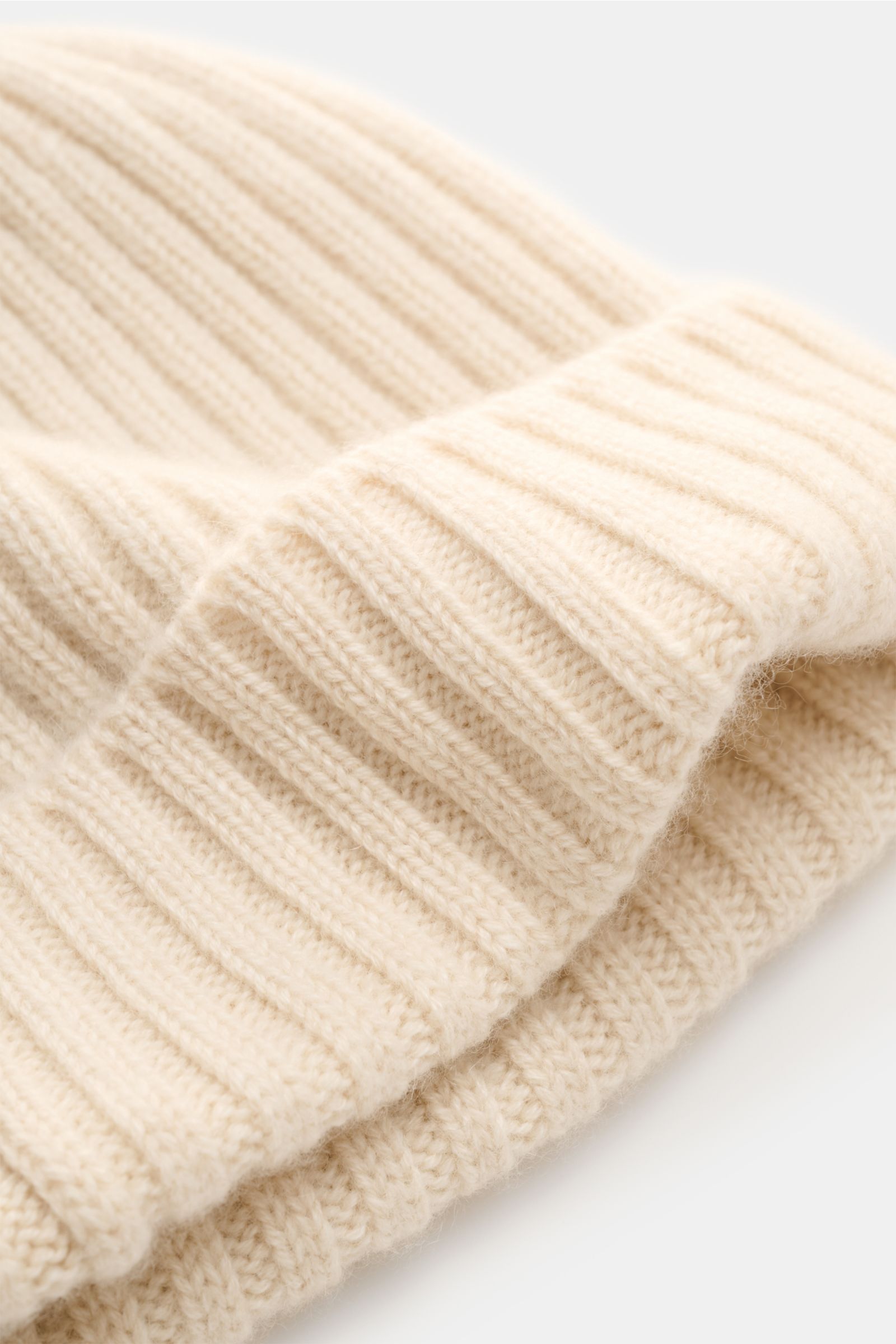 Fedeli Cashmere Mütze creme in Nahaufnahme, breiter Rippstrick, weicher Griff, variabler Umschlag, reiner Cashmere, mittelfeines Strickbild.
