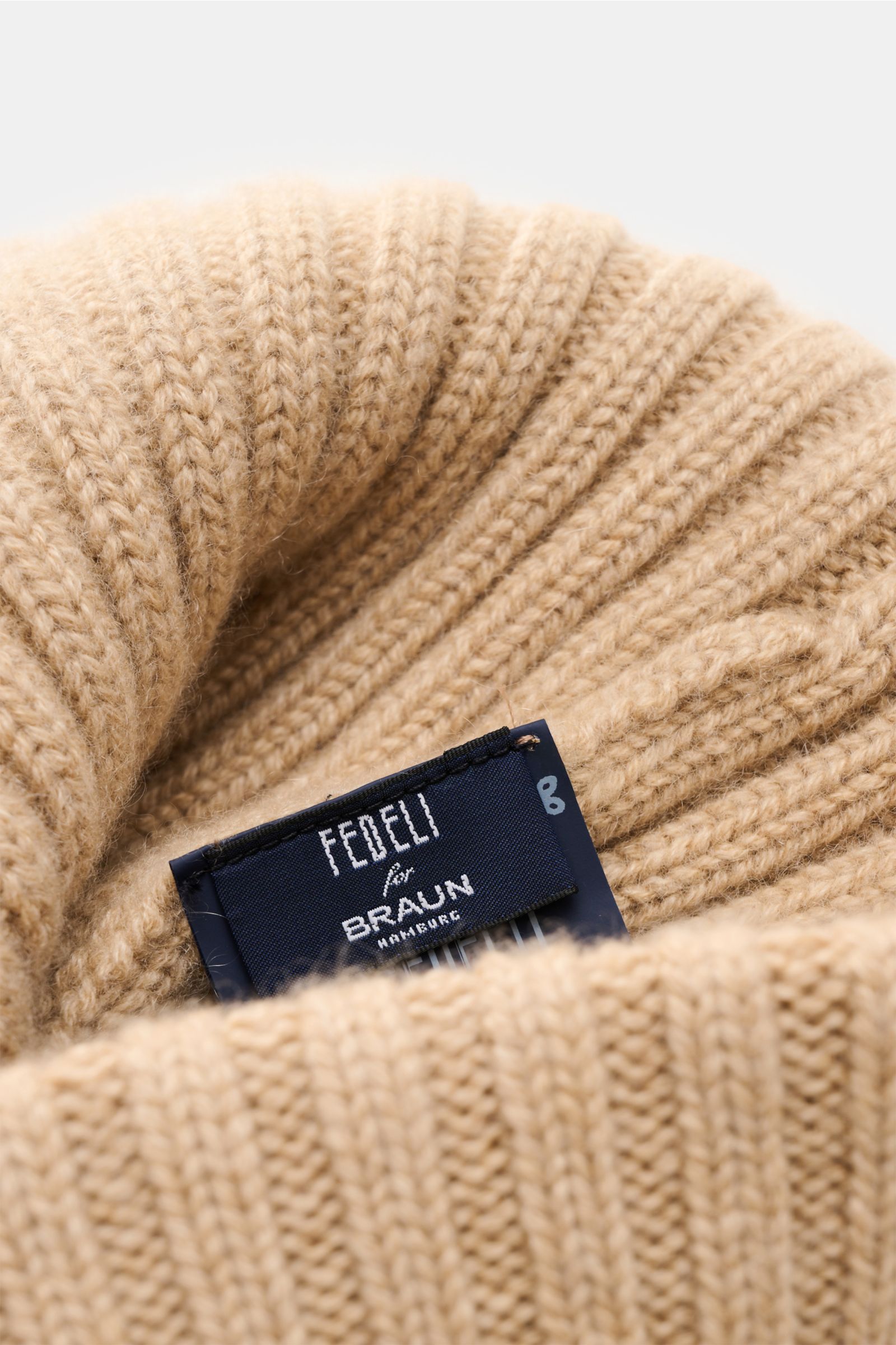 Close-up front view of the Fedeli Cashmere beanie beige showcasing its wide rib knit, medium-fine knit, and adjustable turn-up with label.

Description: With this comfortable beanie, Italian label FEDELI presents a sophisticated accessory in smooth cas