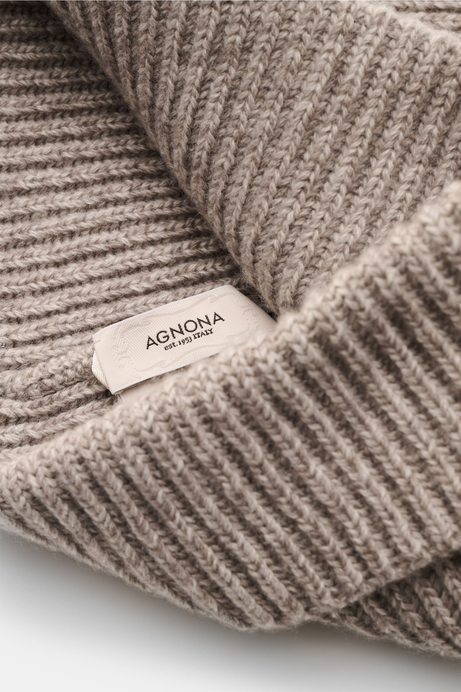 A close-up front angle of the Agnona Cashmere Mütze sand meliert showing its soft, ribbed patent knit pattern and narrow cuff with a visible AGNONA label. Für warme Wintermomente mit Stil: Diese Patentstrickmütze von AGNONA aus reinem Cashmere mit Umschla