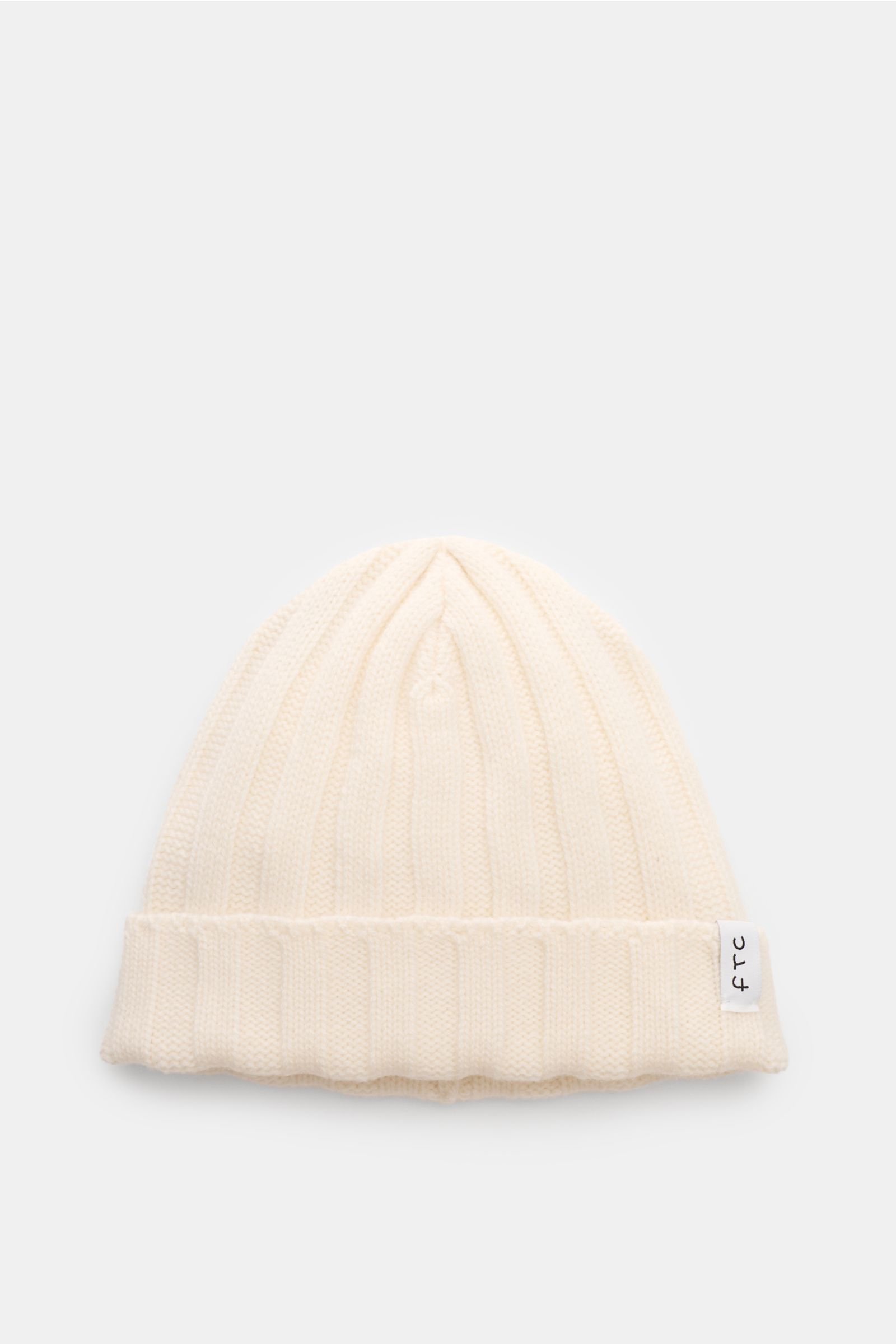 FTC Cashmere Mütze creme aus feinstem Fair-Trade-Cashmere, weicher Griff, Rippstrick, mittelfein, mit schmalem Umschlag und FTC-Weblabel, frontal fotografiert.