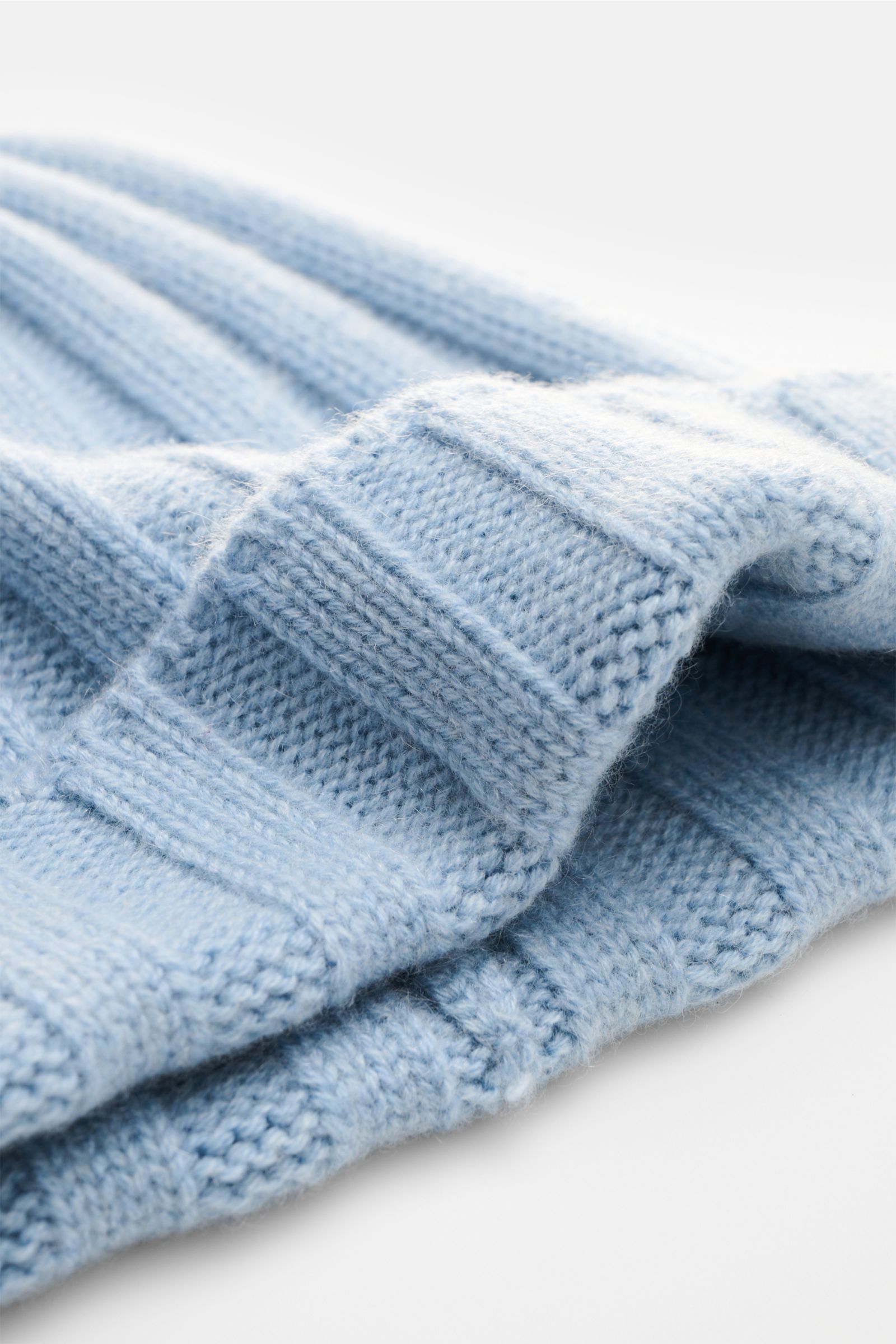 Nahaufnahme der FTC Cashmere Mütze hellblau aus Fair-Trade-Cashmere mit weichem Rippstrick und schmalem Umschlag, perspektivisch fotografiert.