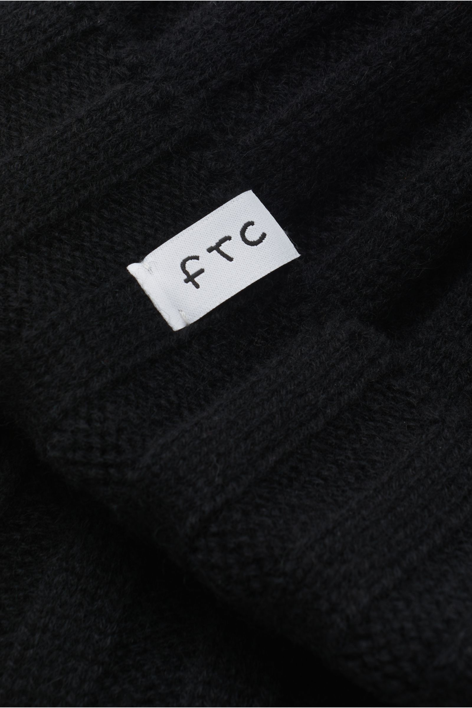 Nahaufnahme der FTC Cashmere Mütze schwarz aus feinstem Fair-Trade-Cashmere mit Rippstrickmuster und schmalem Umschlag.