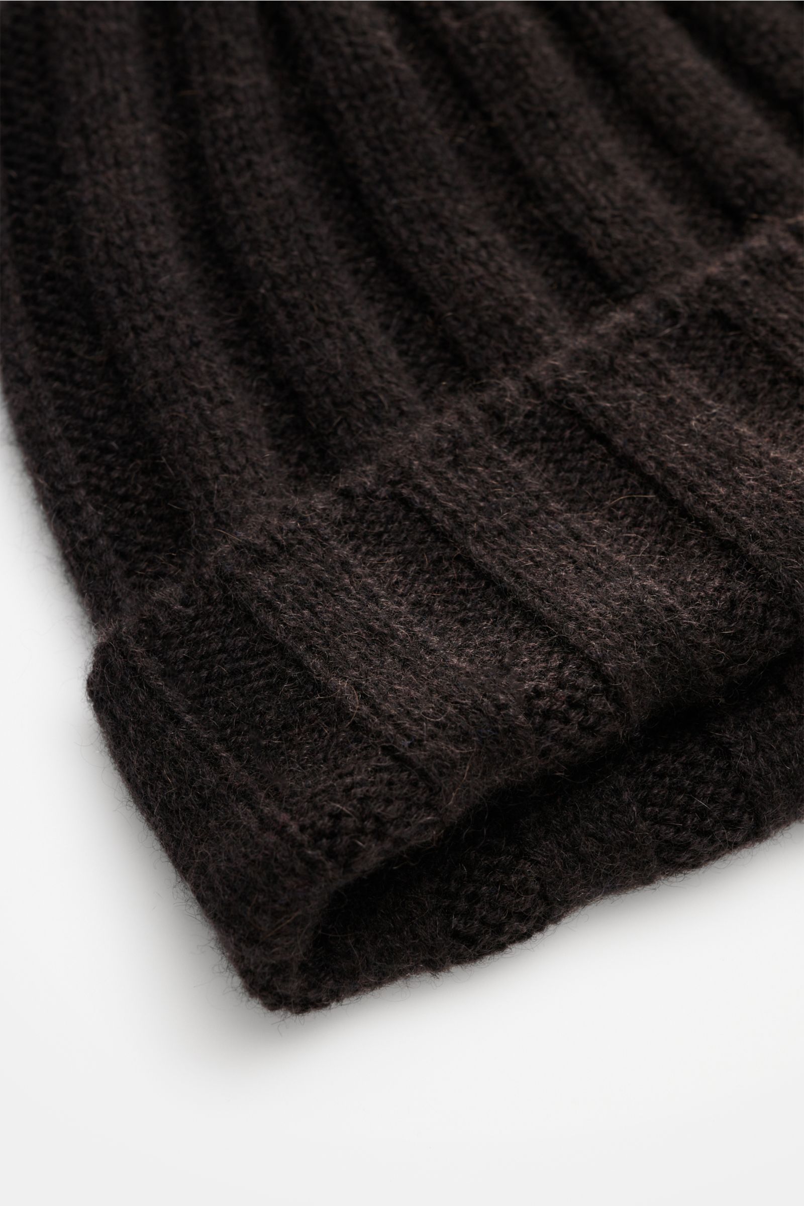Nahaufnahme der FTC Cashmere Mütze dunkelbraun aus feinem Fair-Trade-Cashmere mit Rippstrickmuster und schmalem Umschlag.