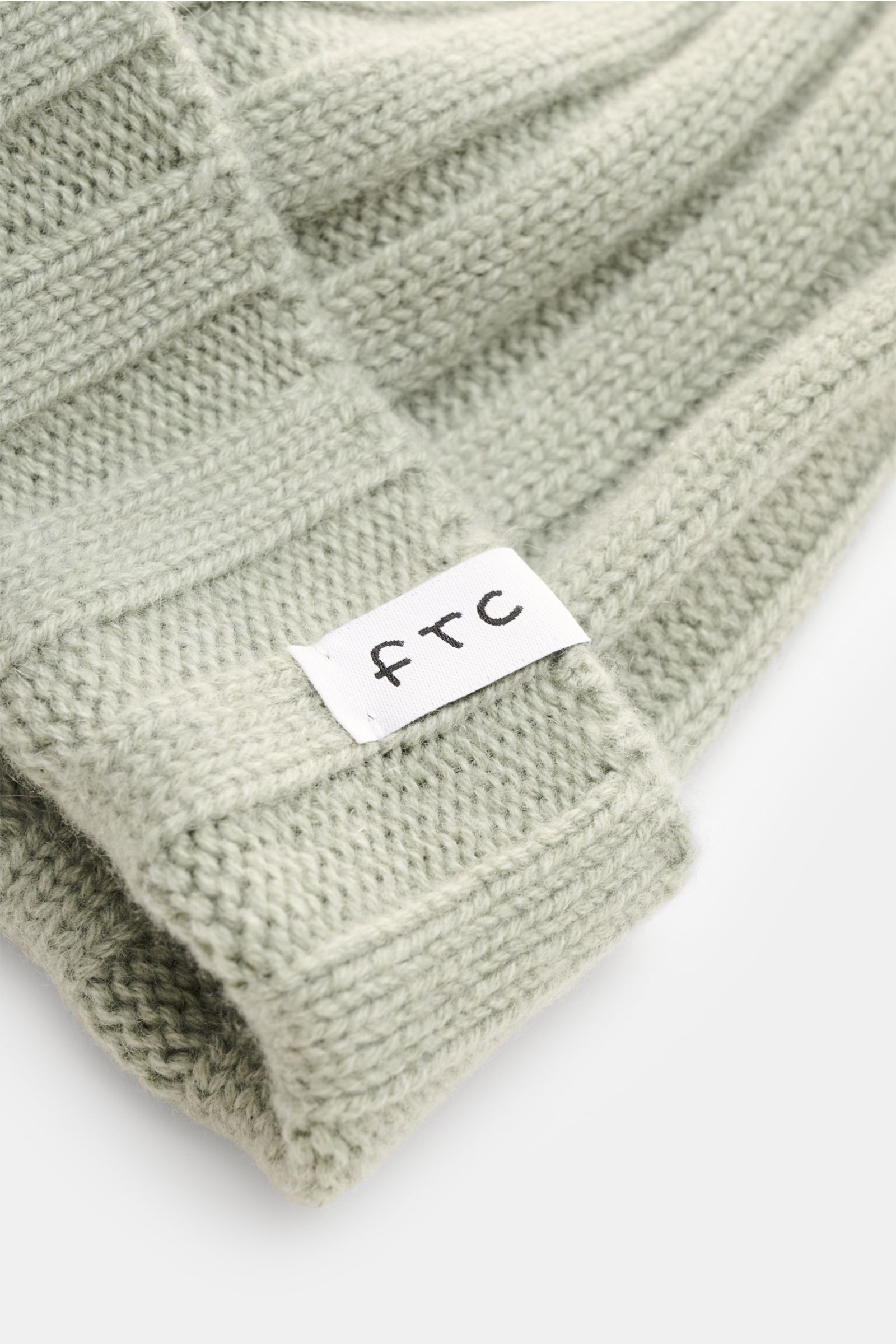 FTC Cashmere Mütze graugrün aus feinstem Fair-Trade-Cashmere, Rippstrick, mittelfein, schmaler Umschlag mit FTC-Label, Nahaufnahme schräg oben