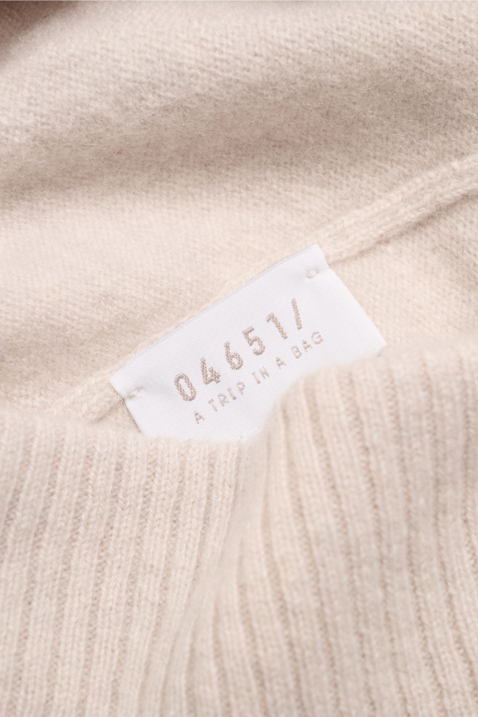 04651/ A trip in a bag Cashmere Mütze beige aus reiner Cashmere, feinem Strickbild mit weichem Griff, Umschlag in Rippstrick, Nahaufnahme von innen mit Label.