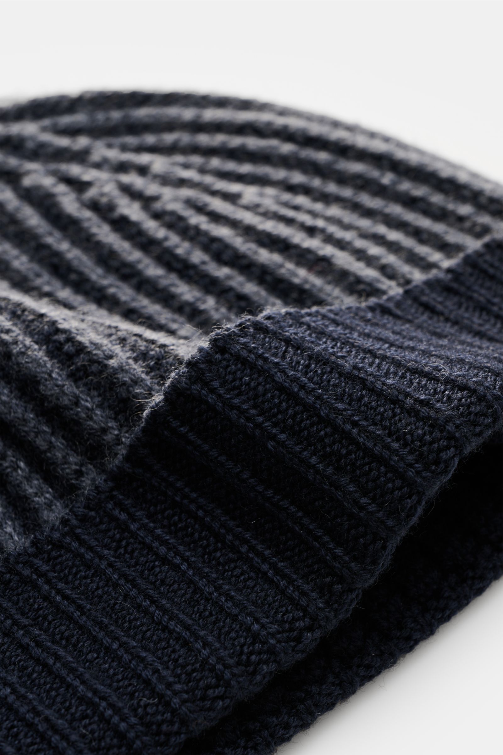 Close-up side view of the 04651/ A trip in a bag Wool beanie 'Foggy Hat' navy showing its rib knit pattern and small turn-up.

Description:  
A stylish winter essential: The wool beanie 'Foggy Hat' by 04651/ A TRIP IN A BAG is an indispensable companio