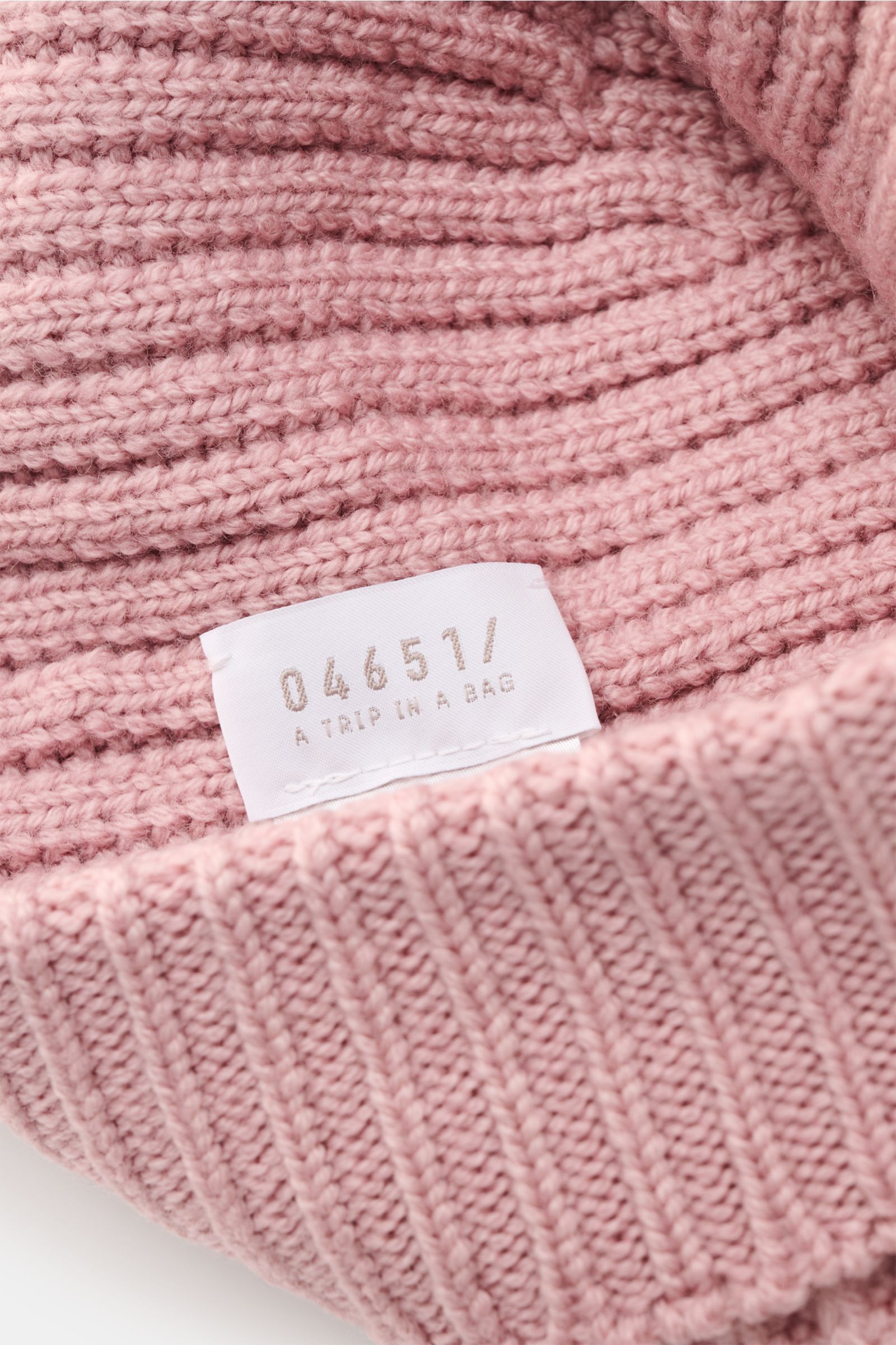 Close-up view of the 04651/ A trip in a bag Wollmütze 'Foggy Hat' altrosa showing its ribbed knit pattern, narrow cuff, and brand label inside.

Description: Stilvolles Winter-Essential: Die 'Foggy Hat' Wollmütze von 04651/ A TRIP IN A BAG wird mit ihr