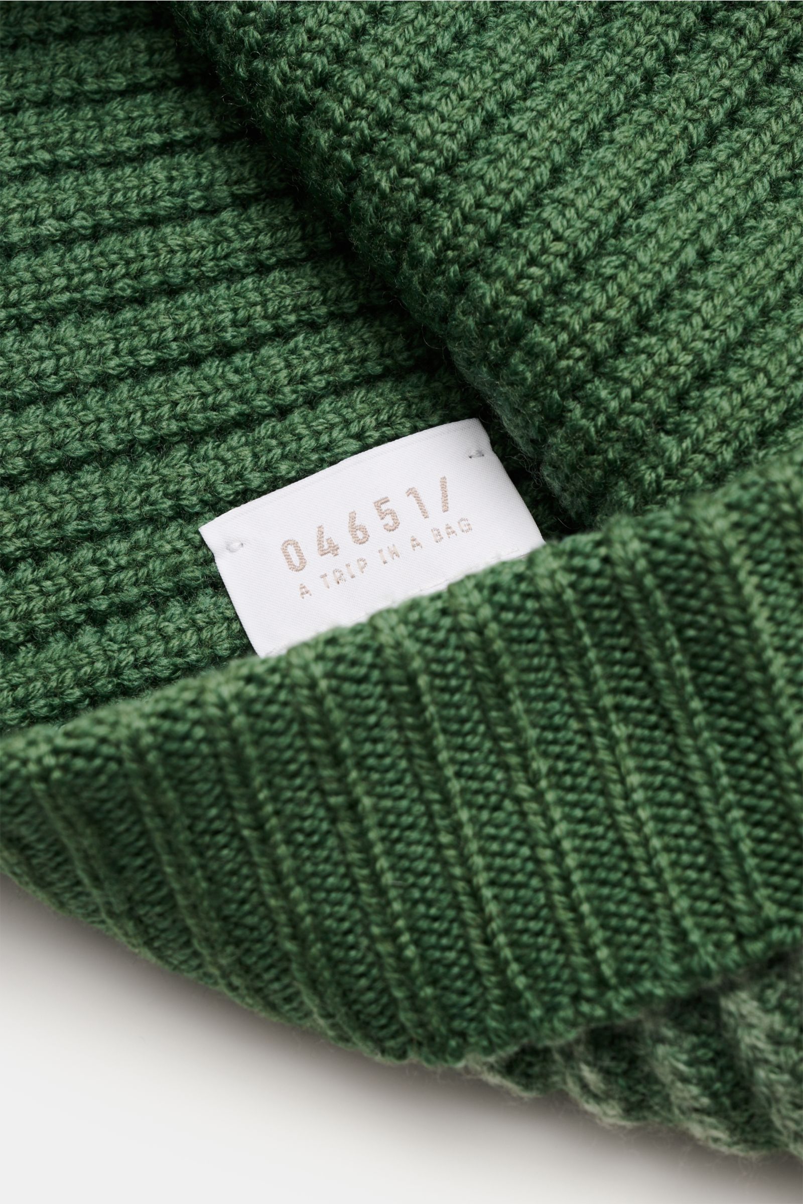 Nahaufnahme aus schräger Perspektive der 04651/ A trip in a bag Wollmütze 'Foggy Hat' grün mit schmalem Umschlag, Rippstrickmuster, weicher reiner Wolle, garment dyed.