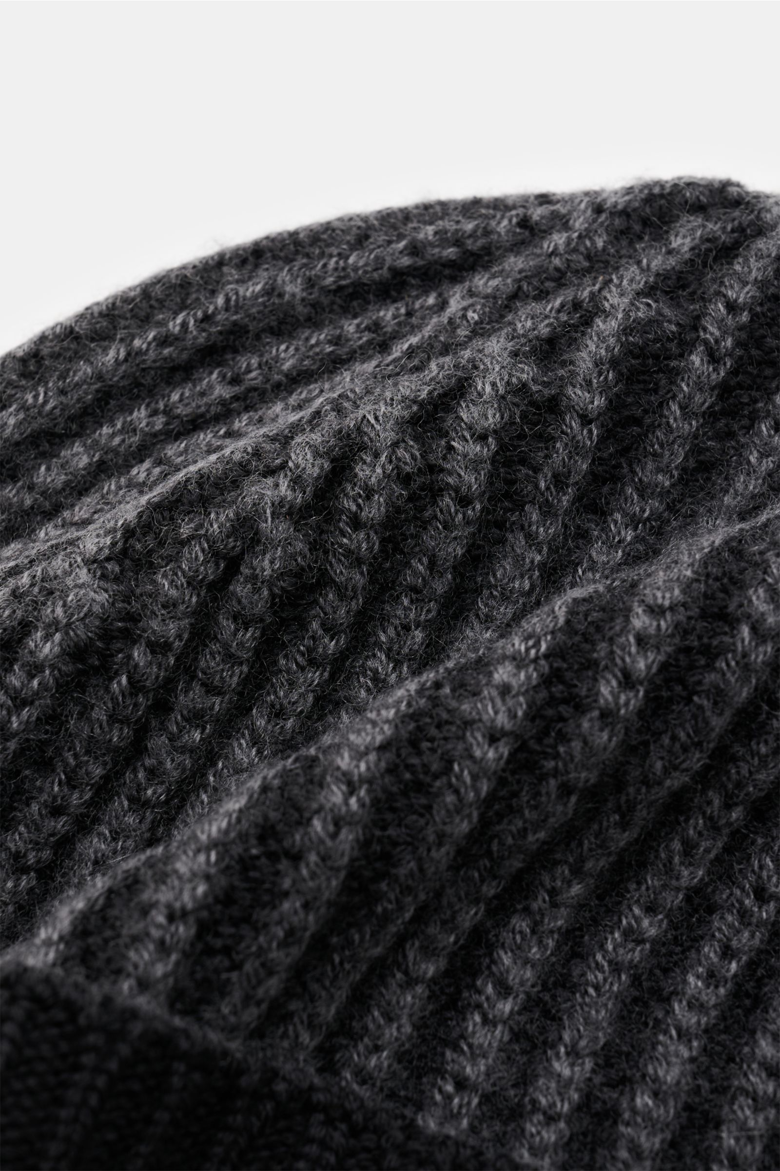 Close-up shot from a side angle of the 04651/ A trip in a bag Wollmütze 'Foggy Hat' schwarz showing its soft, garment dyed pure wool rib knit with narrow cuff.