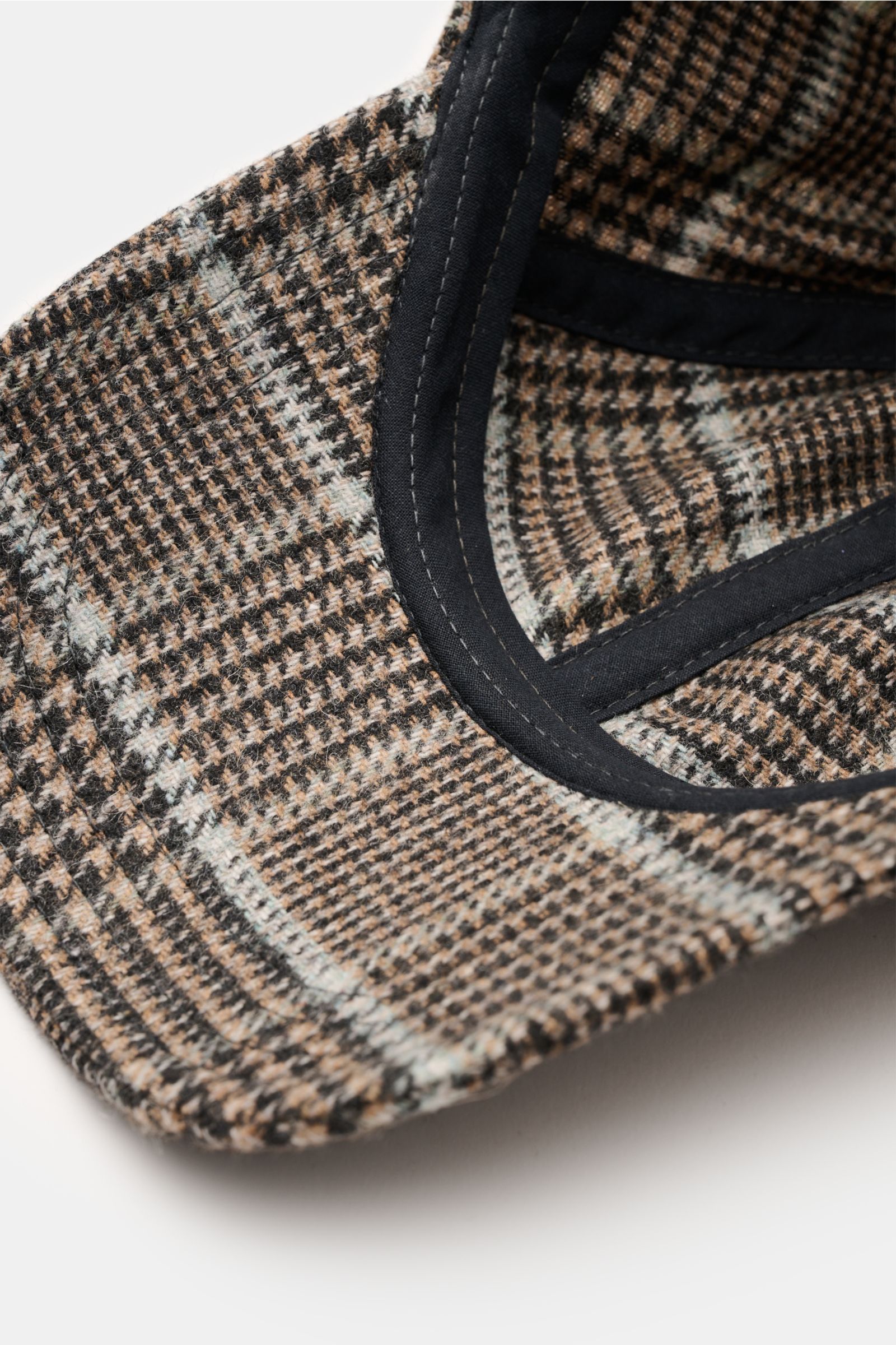 Close-up of the inside and front brim of the 04651/ A trip in a bag Baseball-Cap 'Check' hellbraun/schwarz/rauchblau kariert, showing its classic Glencheck pattern in light brown, black, and smoky blue. The image is photographed from a top-front angle hig