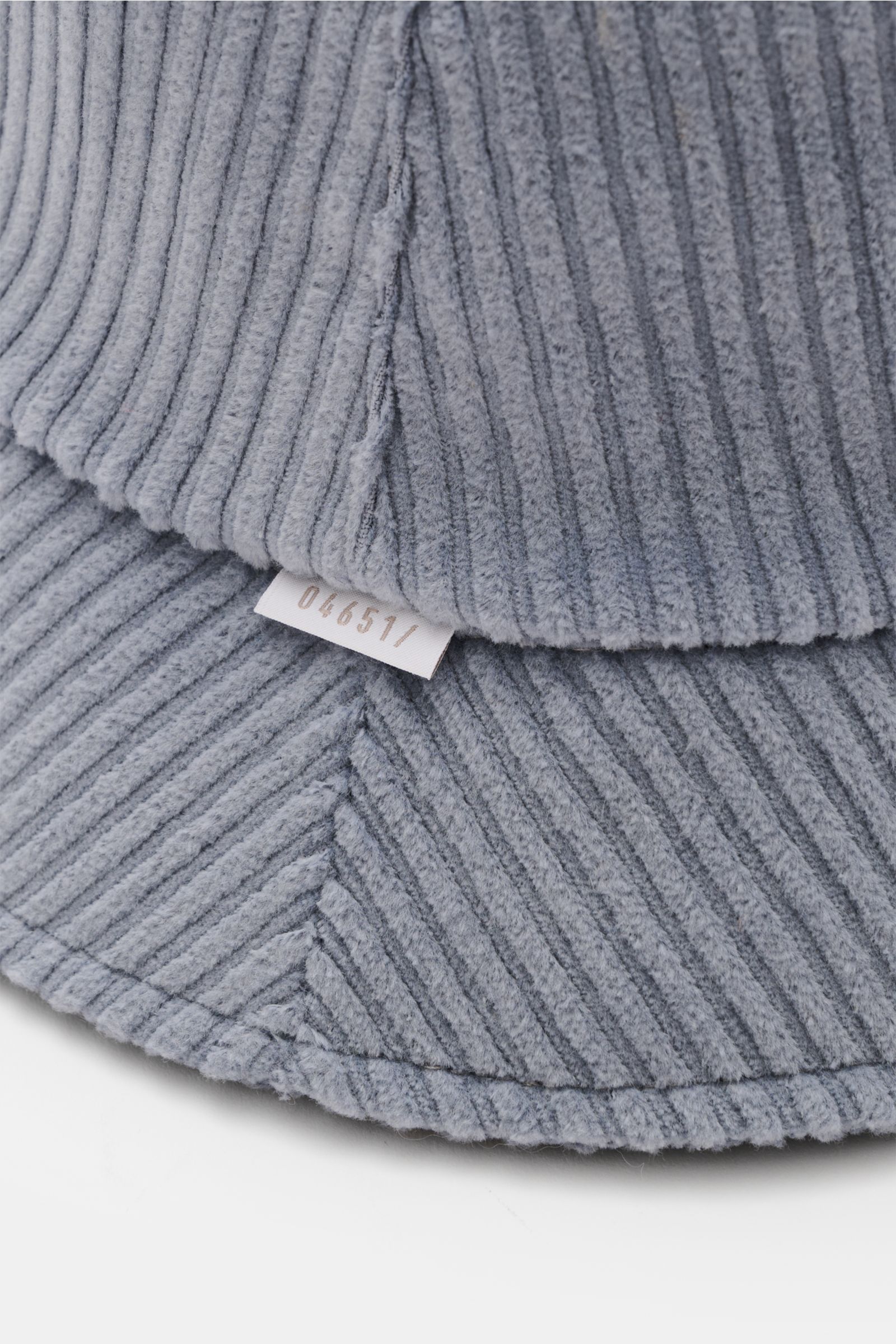 Nahaufnahme des 04651/ A trip in a bag Cord Bucket Hat rauchblau aus softem Baumwoll-Cord mit Fleece-Futter, schmaler Krempe und kleinem Weblabel.