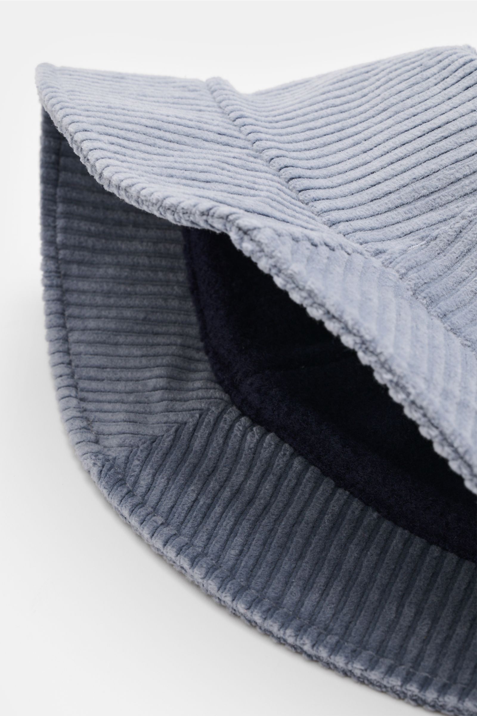 04651/ A trip in a bag Cord Bucket Hat rauchblau aus softem Baumwoll-Cord mit schmaler Krempe, Fleece-Futter, Weblabel, von schräg oben fotografiert.