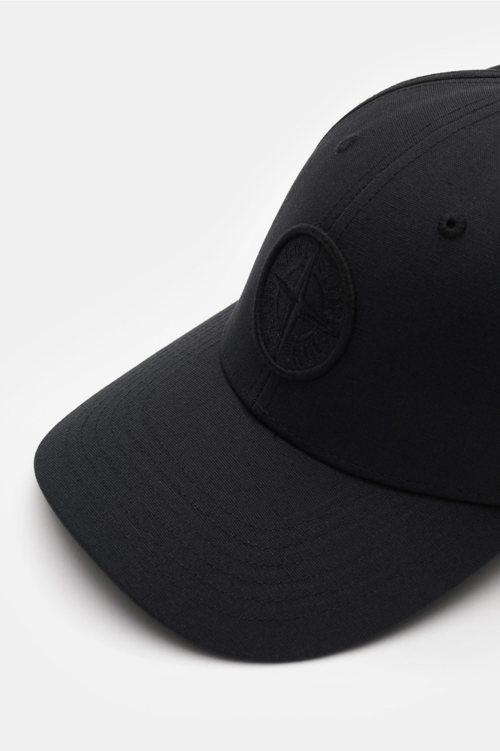 Stone Island Baseball-Cap schwarz shown from a front-left angle, made of pure cotton with tonal compass stitching and curved brim.