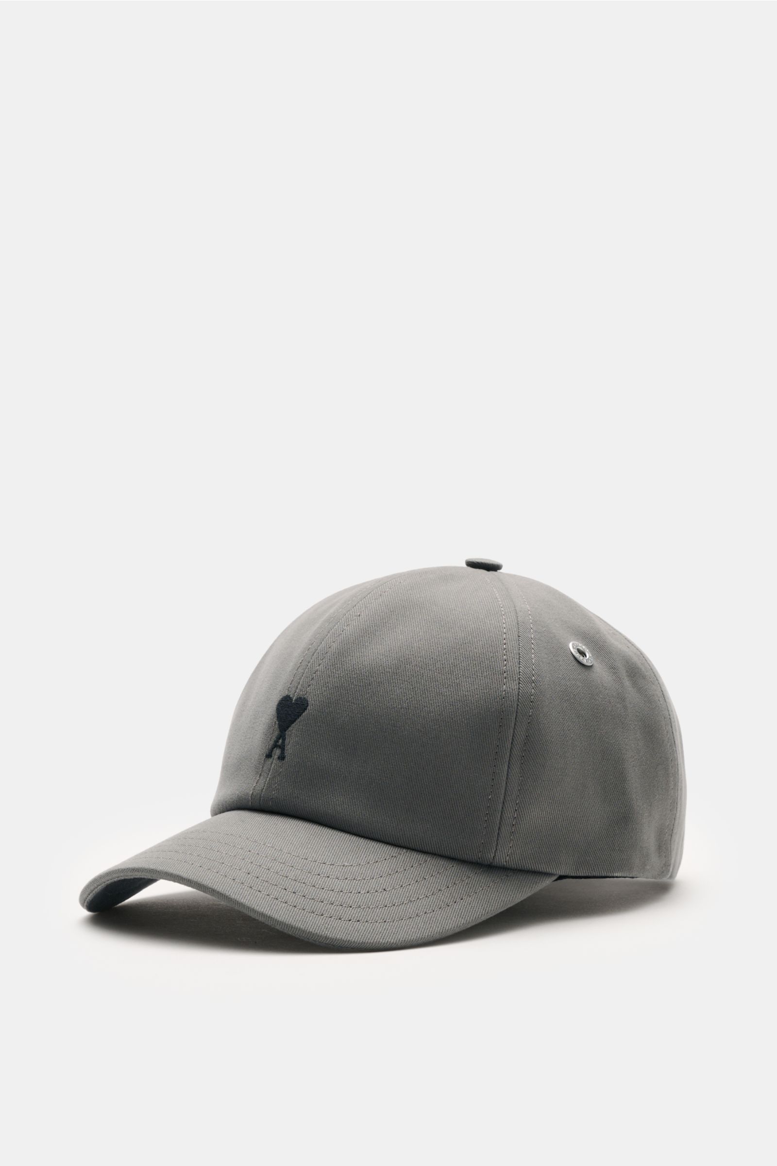 Ami Paris Baseball-Cap dunkelgrau shown from a front-left angle, made of pure cotton with a soft feel, curved brim, contrasting heart logo stitching, and adjustable closure. A french affair: Diese Baseball-Cap aus reiner Baumwolle von AMI PARIS ergänzt