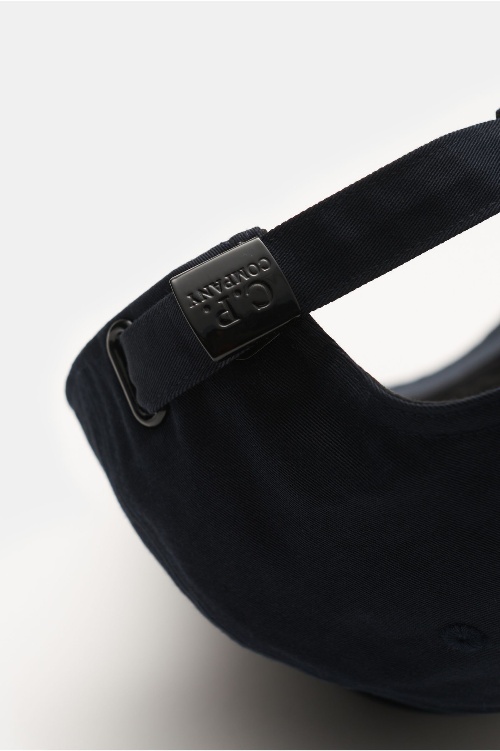 Close-up rear view of the C.P. Company Baseball-Cap navy, showing the adjustable strap with black metal buckle embossed with the brand logo. The clean baseball cap is made from pure cotton gabardine, featuring a fine weave structure, lightweight breathabl