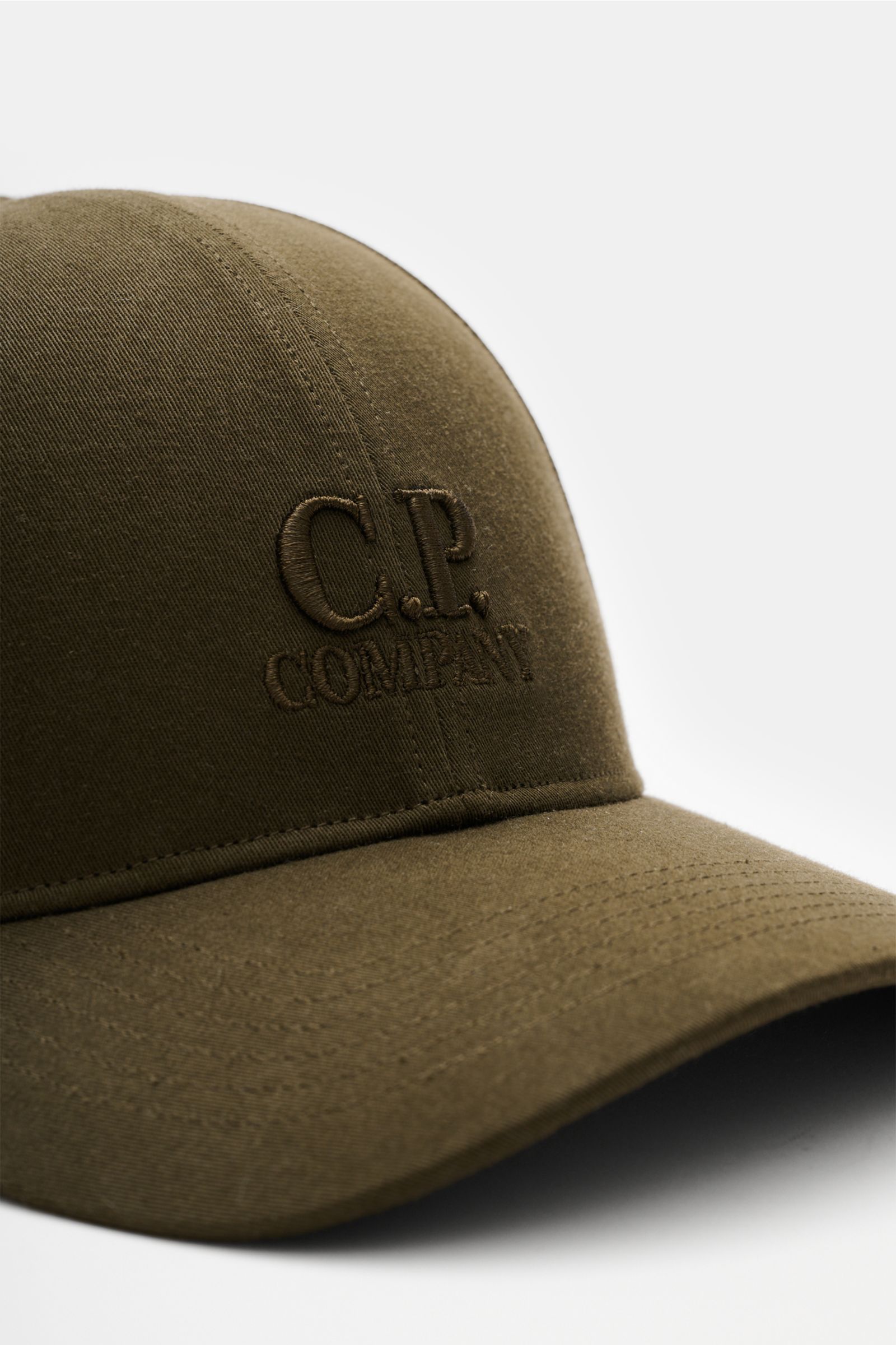 C.P. Company Baseball-Cap khaki shown from a close-up front-side angle, made of pure cotton gabardine with fine weave, lightweight, breathable, garment dyed, featuring three-dimensional logo embroidery and adjustable strap. Die cleane Baseball-Cap aus 