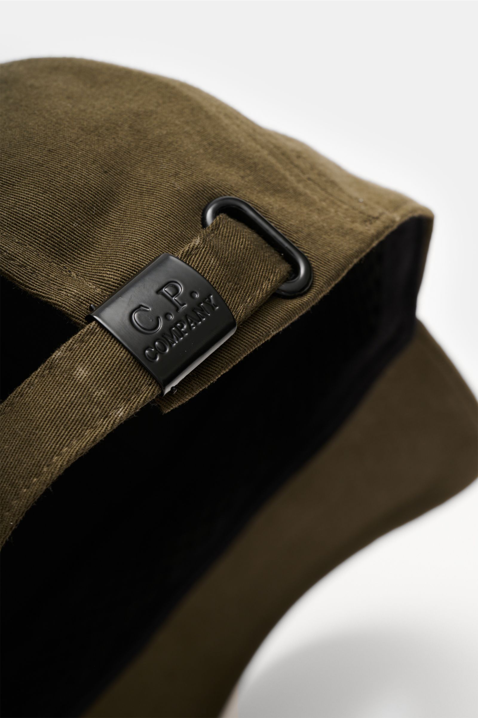 Close-up rear view of the C.P. Company Baseball-Cap khaki, showing the adjustable strap with black metal buckle embossed with the brand's 3D logo. Die cleane Baseball-Cap aus reinem Baumwoll-Gabardine von C.P. COMPANY mit reliefartiger Stickerei ist nicht