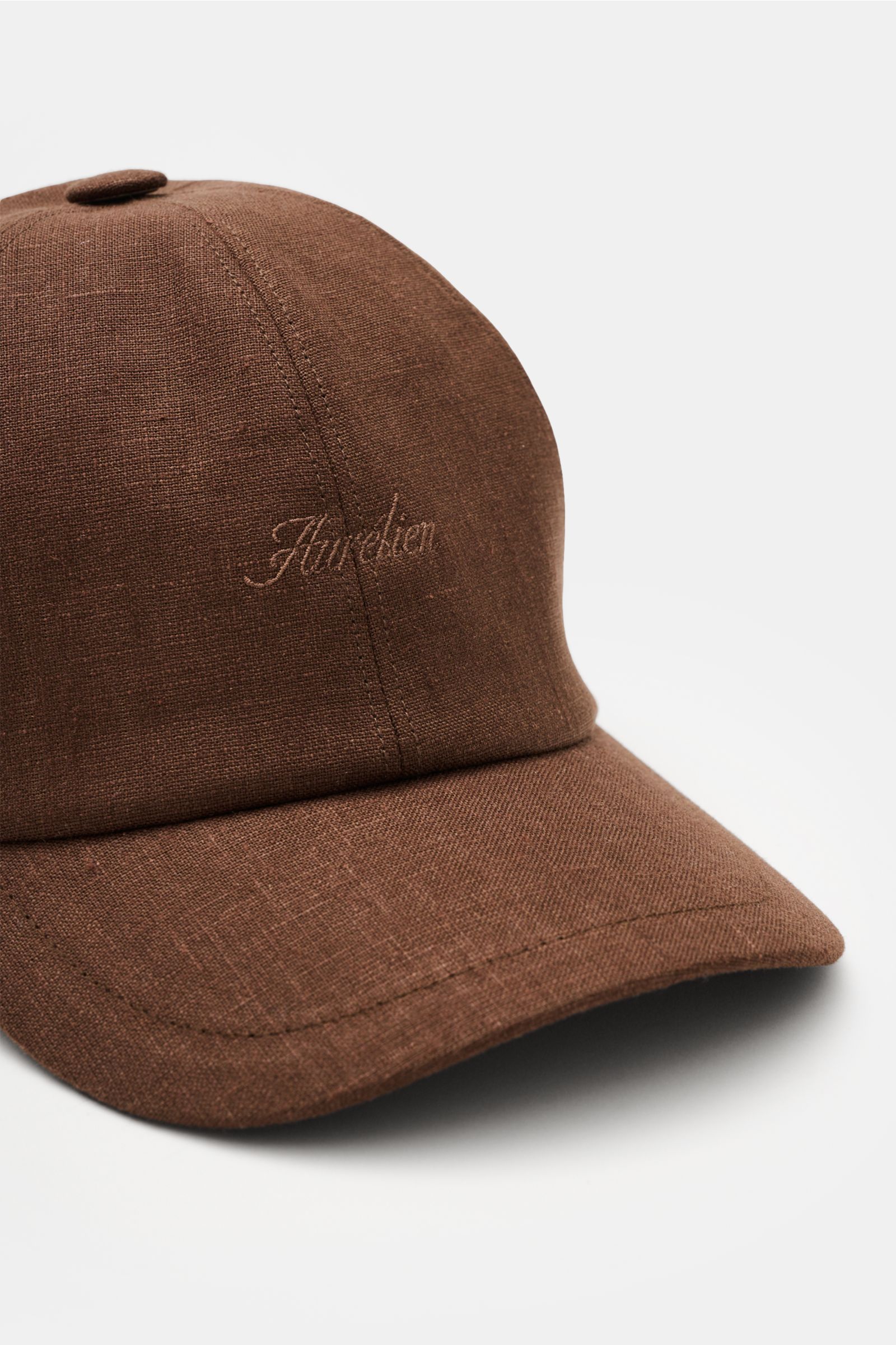 Aurélien Baseball-Cap dunkelbraun aus reinem Leinen, Six-Panel-Stil, gebogener Schirm, tonales Logo-Stitching, Baumwollfutter, leichte griffige Haptik, Nahaufnahme schräg von vorn.