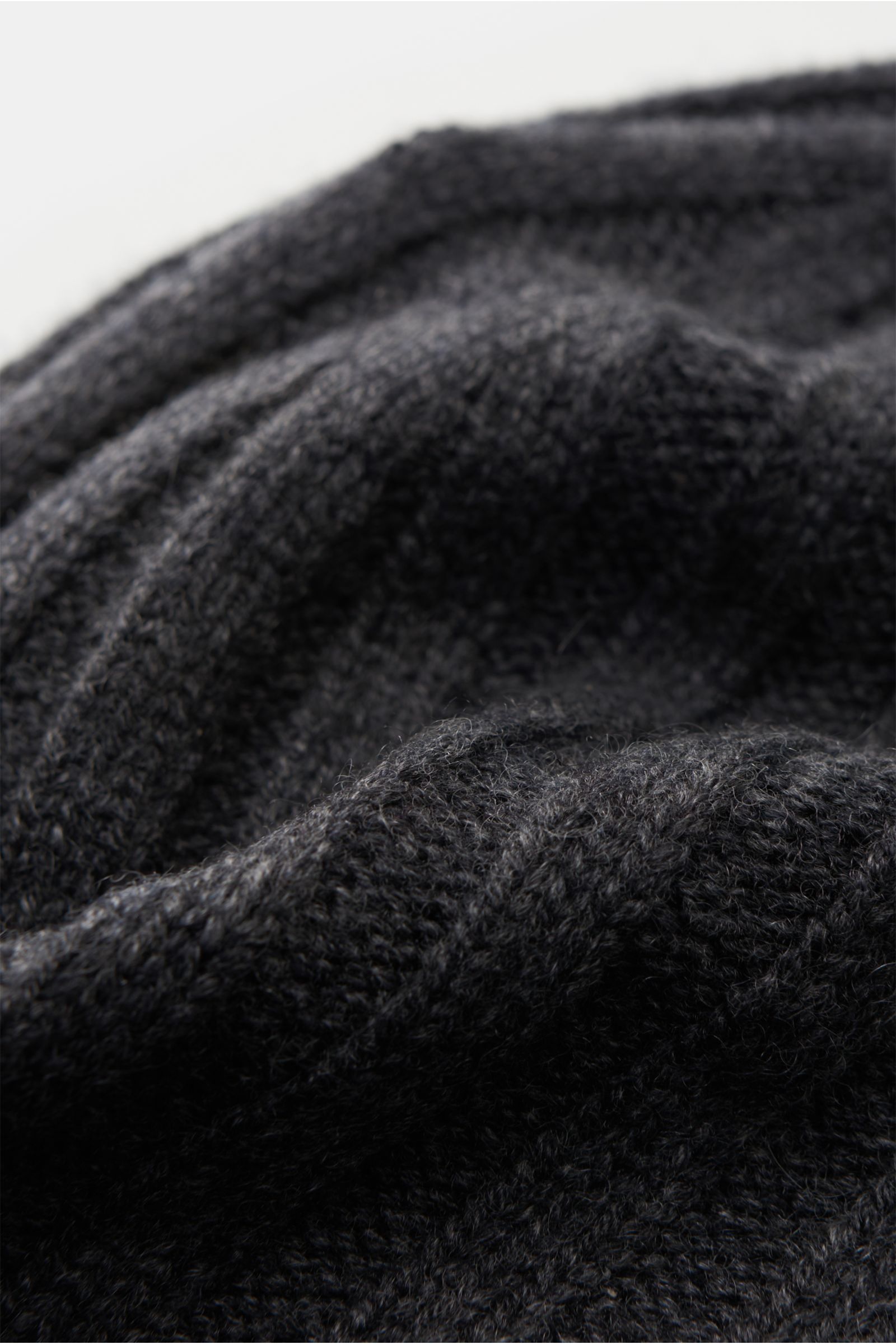 Nahaufnahme aus seitlicher Perspektive der von Braun Cashmere Mütze anthrazit meliert mit feinem Rippstrickmuster, schmalem Umschlag, sehr weichem Griff aus reinem mongolischen Cashmere.