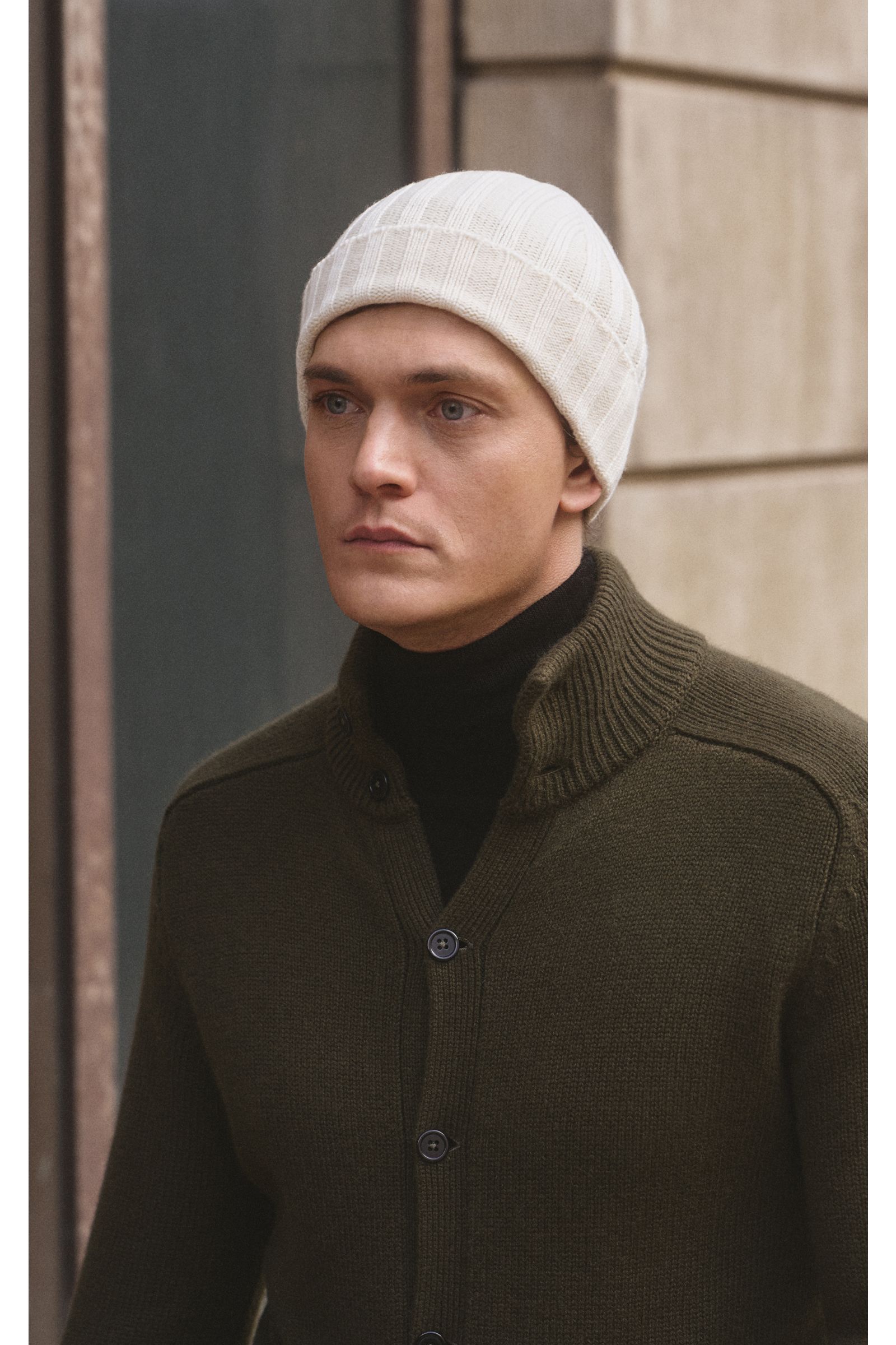 von Braun Cashmere Mütze offwhite, klassisches Rippstrickmuster, schmaler Umschlag, sehr weich, feines Strickbild, frontal am Kopf eines Mannes fotografiert.