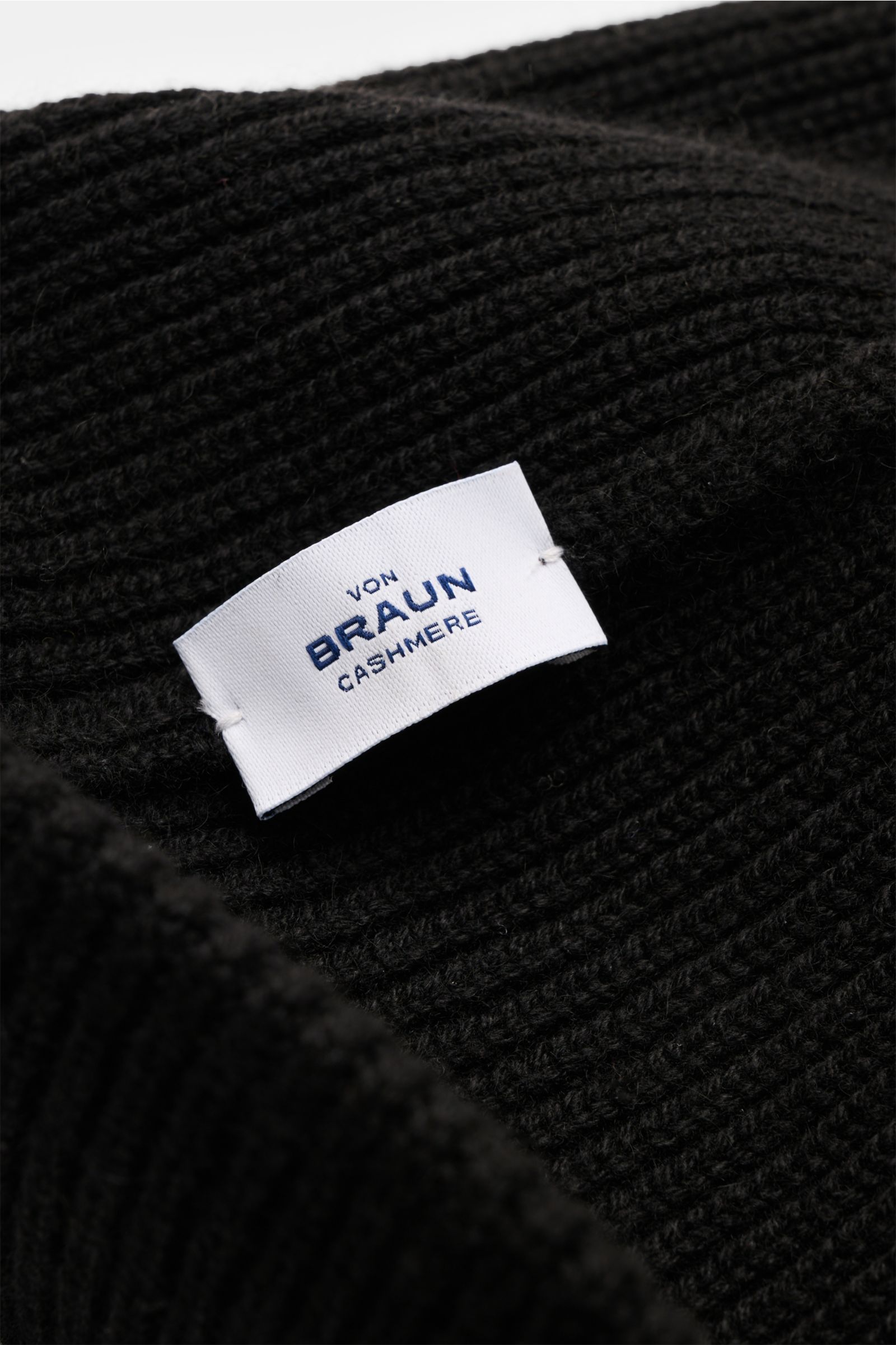 Nahaufnahme der von Braun Cashmere Mütze schwarz aus weichem, feinem Patentstrick mit schmalem Umschlag, Perspektive schräg von oben.