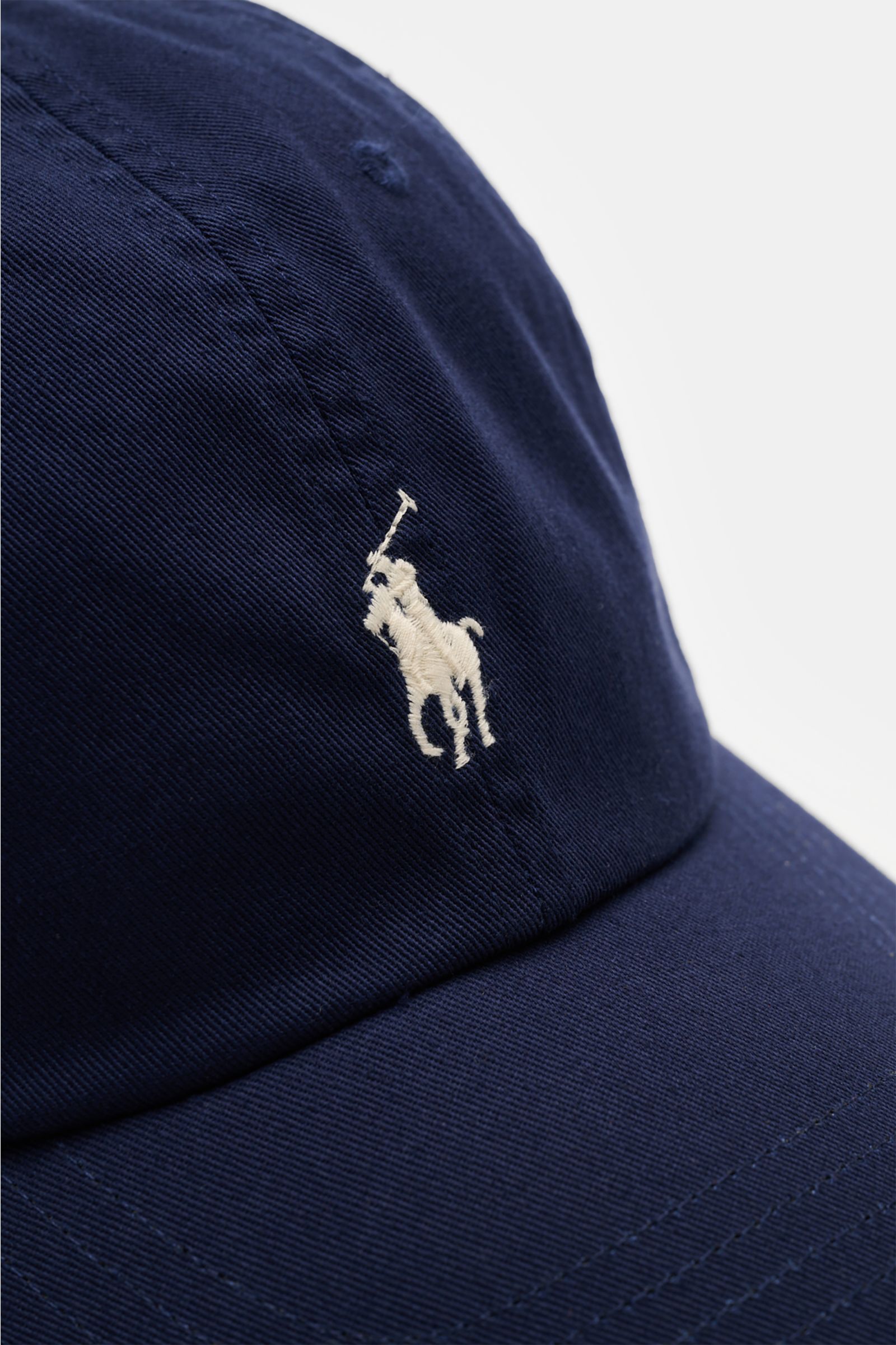 Close-up front-side view of Polo Ralph Lauren Baseball-Cap navy in pure cotton with classic six-panel design and white logo-stitching.

Lässige Looks: Die Baseball-Cap von POLO RALPH LAUREN überzeugt als vielseitiges Accessoire für sportlich-legere Out